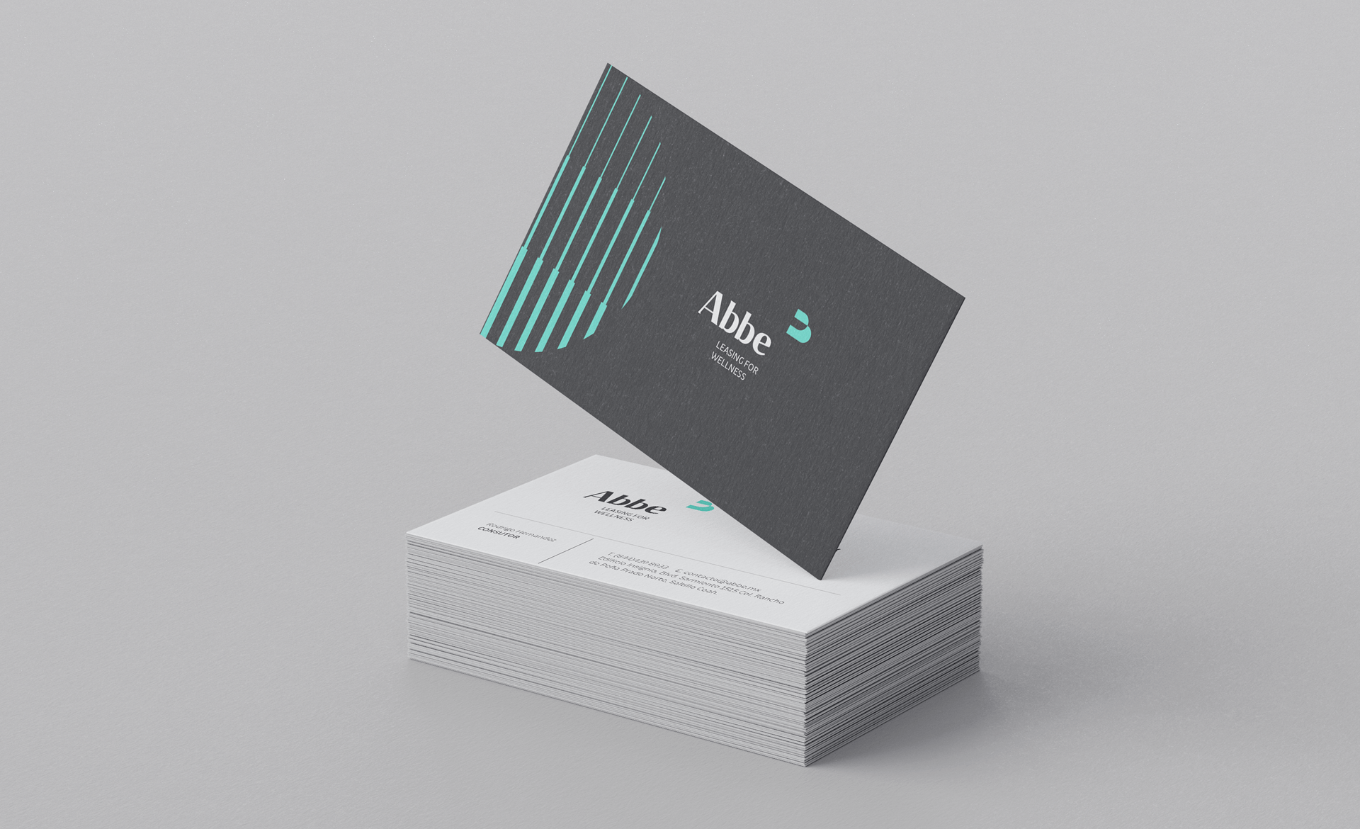 Tarjetas de visita apiladas y una tarjeta sobresaliente con el logo de Abbe y la etiqueta 'Leasing for Wellness' en un fondo de color gris.