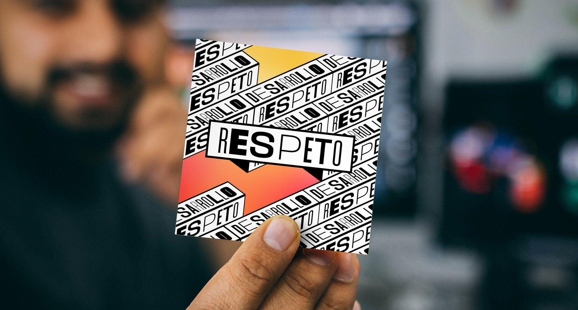 Persona sosteniendo una tarjeta con la palabra 'RESPETO' escrita en letras grandes, con fondo de colores naranja, amarillo y rosa, en un entorno que parece ser un supermercado o tienda.