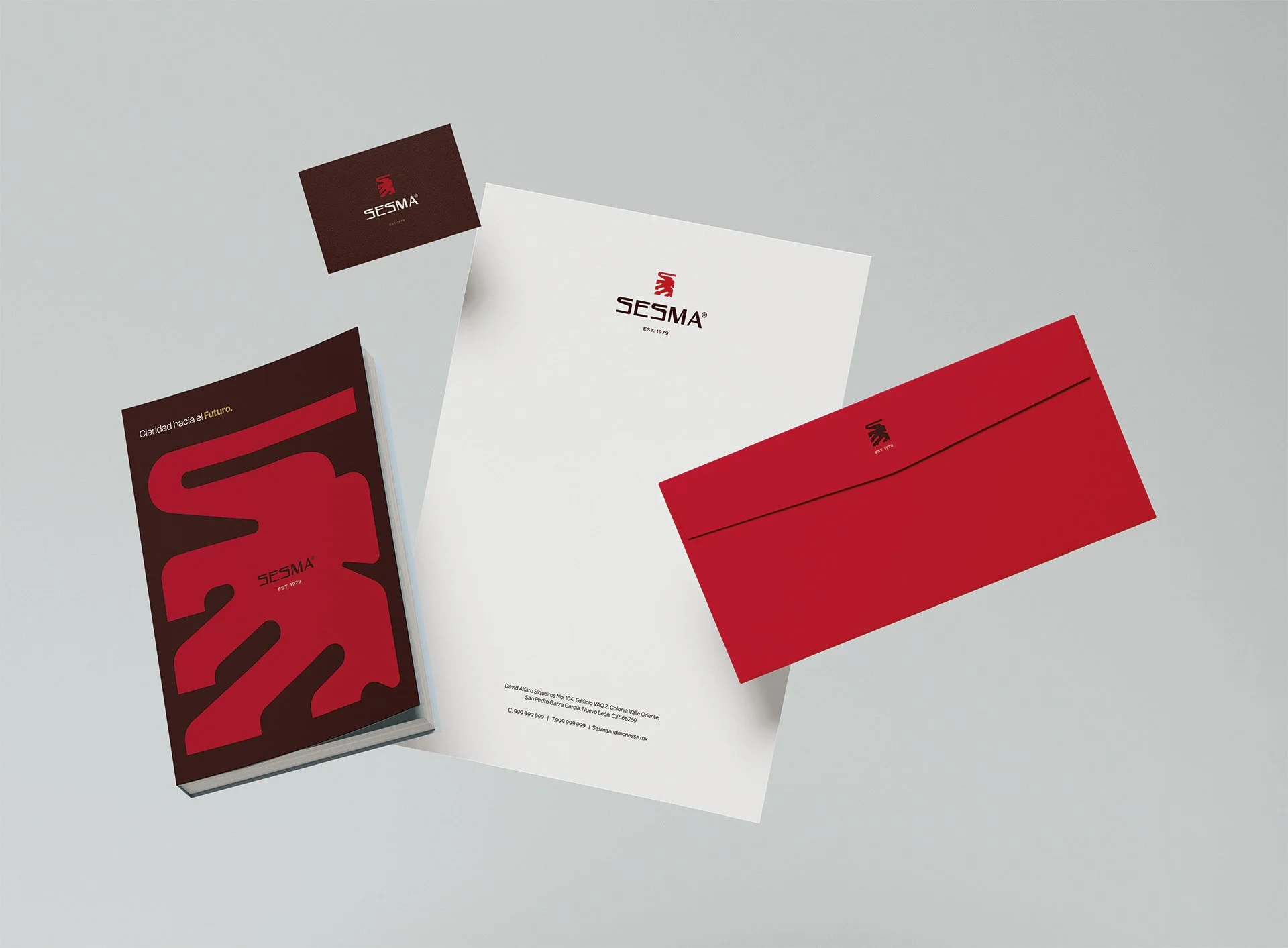 Material de oficina de la marca SESMA, incluyendo tarjetas de presentación, papelería, y sobres en colores rojo, blanco y negro con logotipo y diseño profesional.