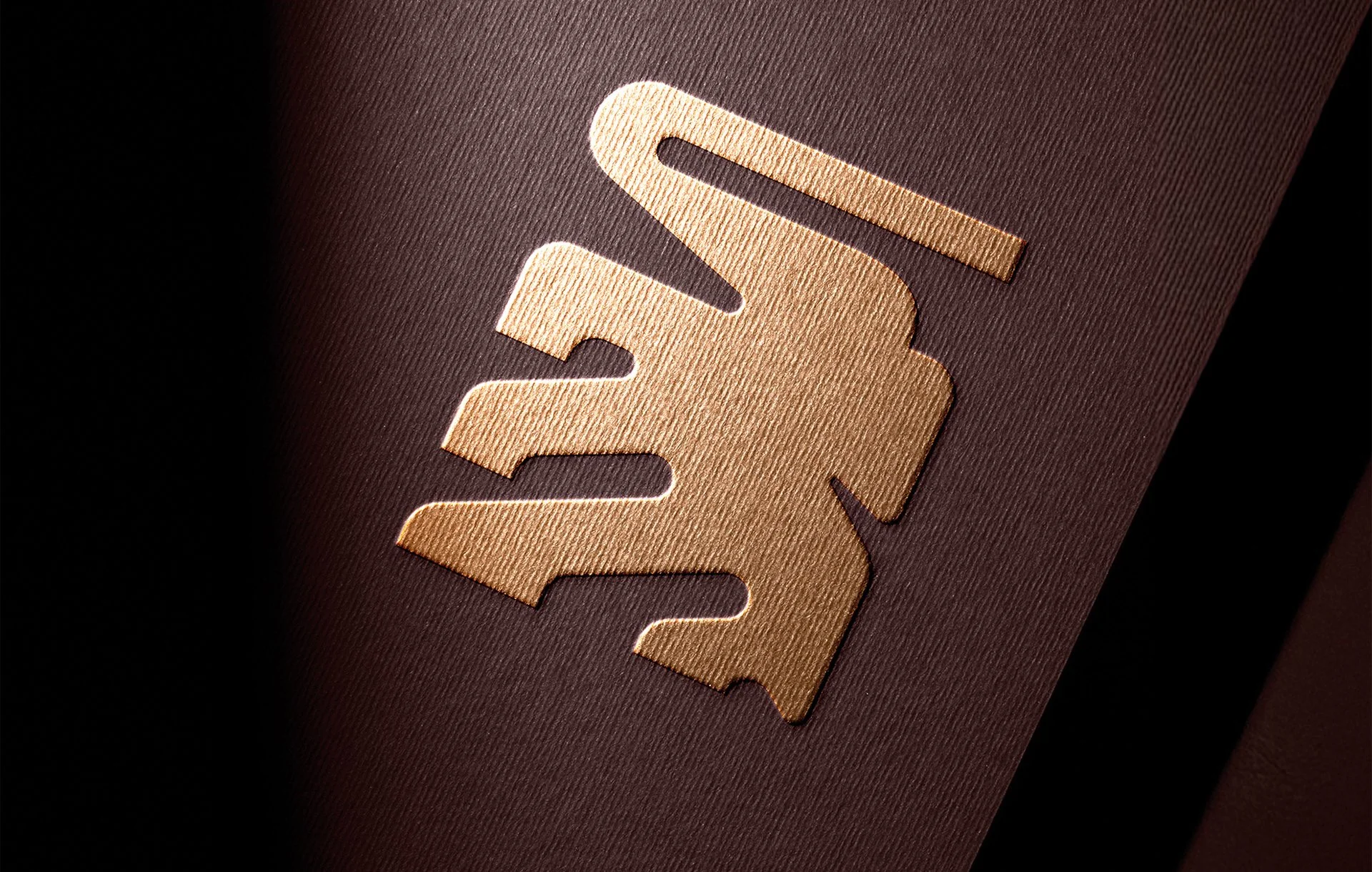 Logotipo en color dorado sobre fondo oscuro.