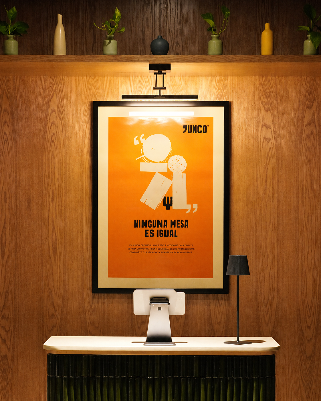 Cartel de color naranja con ilustraciones abstractas de mesas y comida. Texto en español que dice 'Ninguna mesa es igual'. Muebles y plantas decorativas en fondo de madera clara.