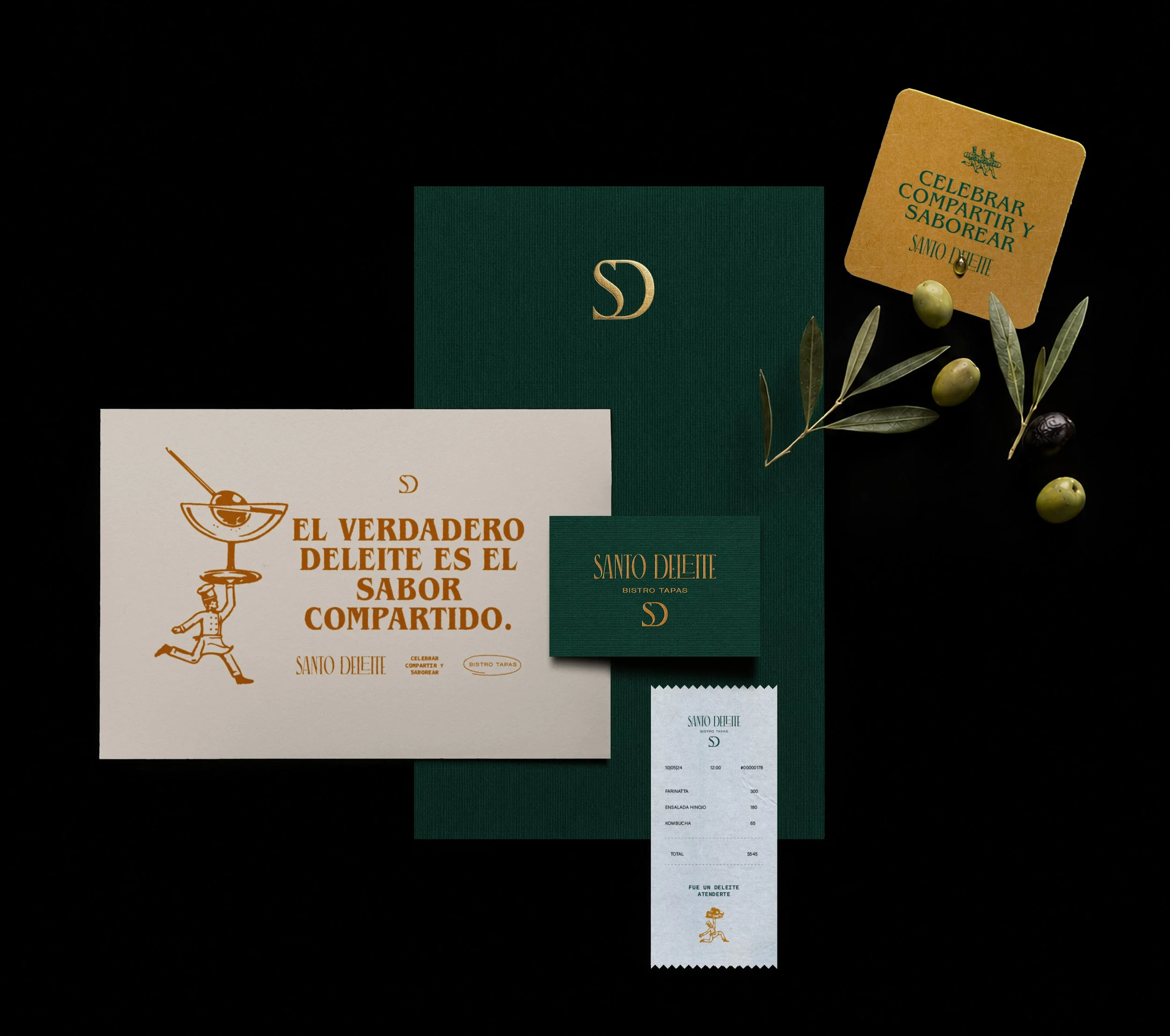 Imagen de varios materiales de papel, incluida una tarjeta con el texto 'Celebrar, compartir y saborear'. También hay hojas de olivo, uvas verdes y una hoja de papel con impresión de un texto en español y una ilustración de una persona con un plato. Un ticket de comida y una tarjeta con letras doradas en un fondo oscuro.