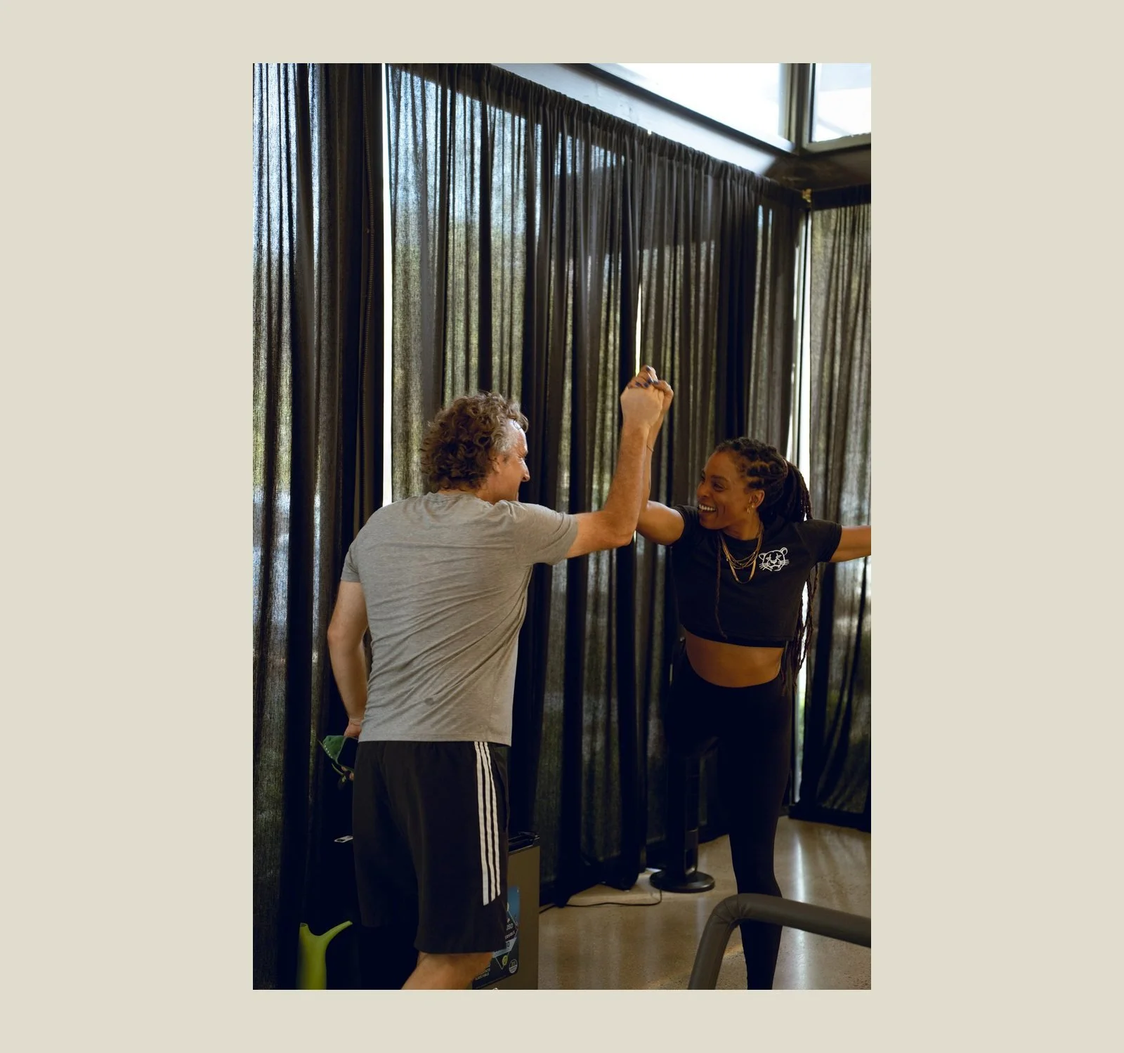 Older adult high-fiving a Pilates instructor after a reformer session at Black Cat Studio in Nosara