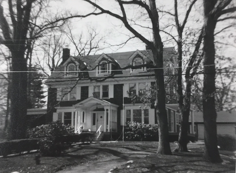 A large, old-fashioned multi-story house with a front porch, surrounded by leafless trees in a yard.