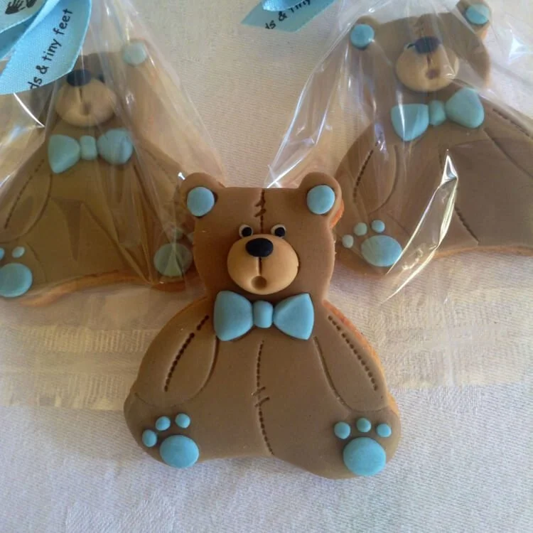 Teddy bear-shaped cookies with blue bow ties and paws, wrapped in clear plastic.