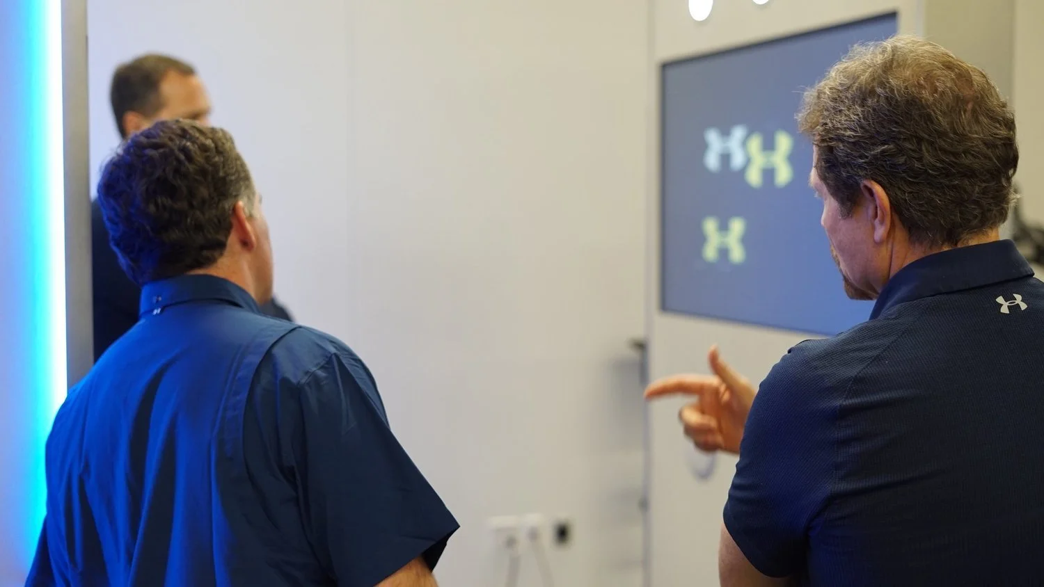 CEO of Under Armour Kevin Plank and CIO of Under Armour Clay Dean having a discussion in front of a screen displaying the Under Armour logo.