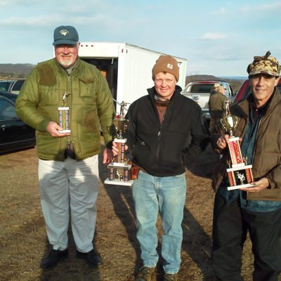 Group of three men holding trophies