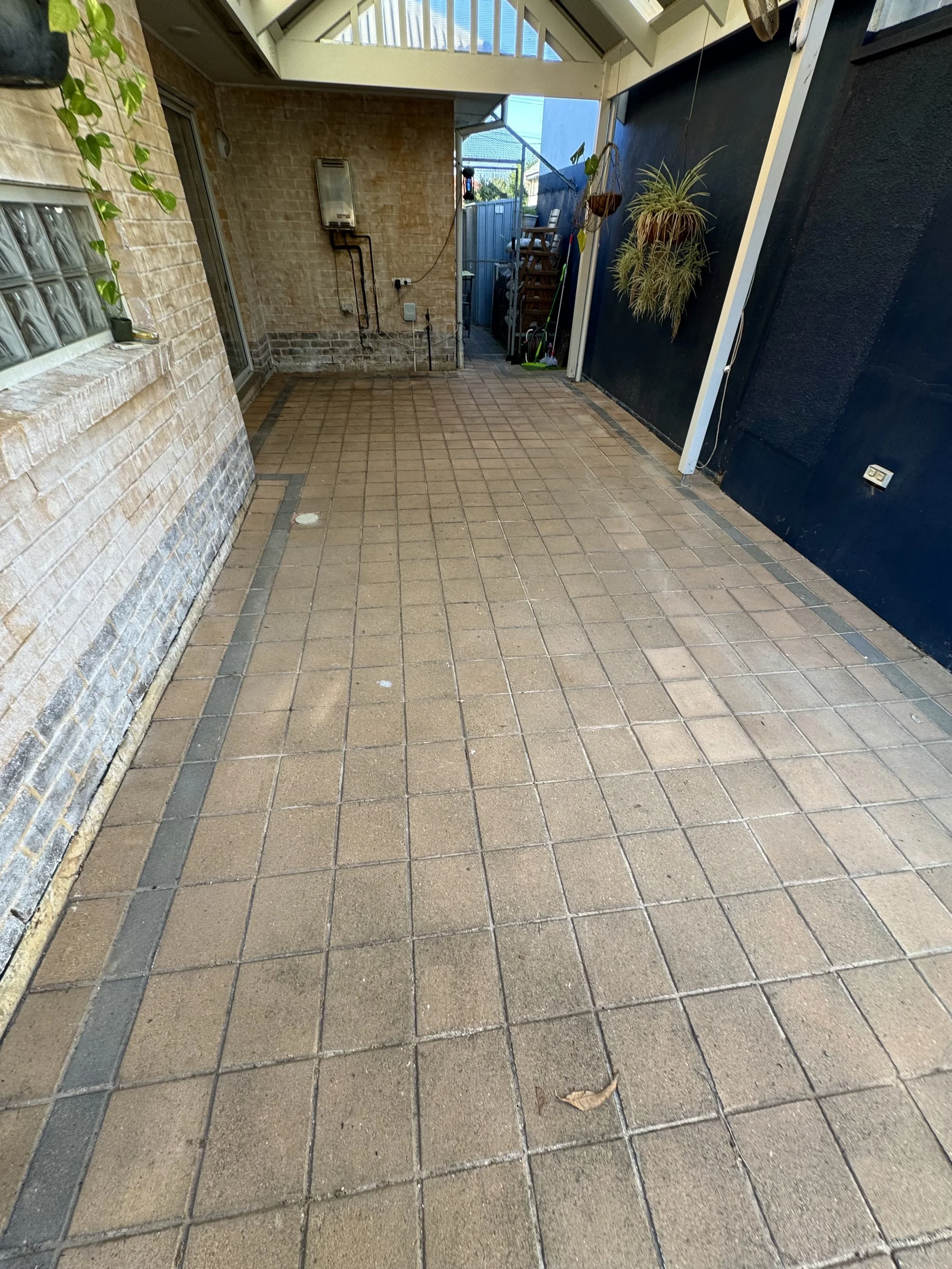 Installation of composite decking over existing pavers, utilising a treated timber sub-frame, raised to align seamlessly with the interior finished floor level.