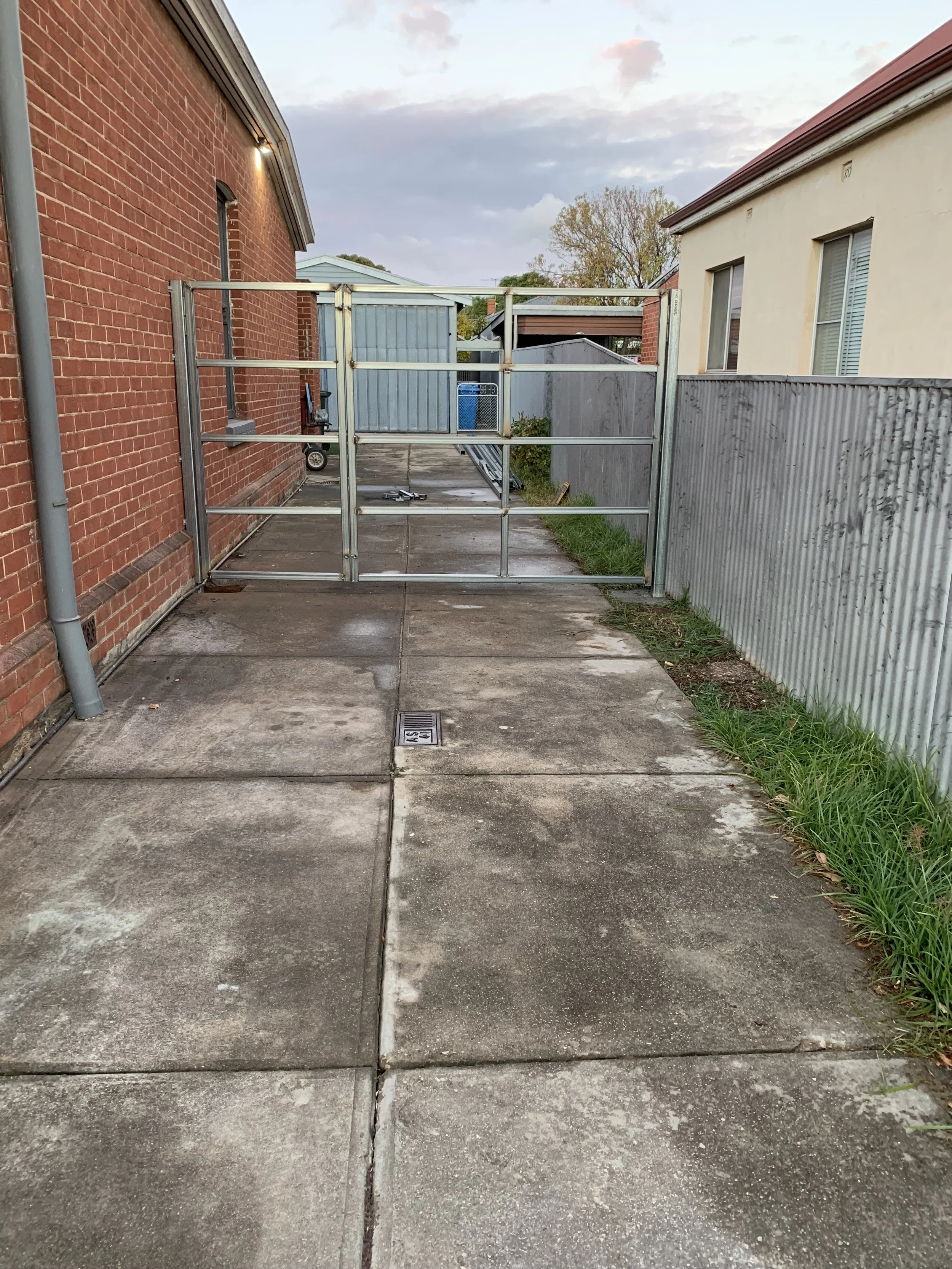 Installation of a steel-framed driveway gate with a personal access entrance, featuring unique trim details to enhance the design, while providing privacy and security.