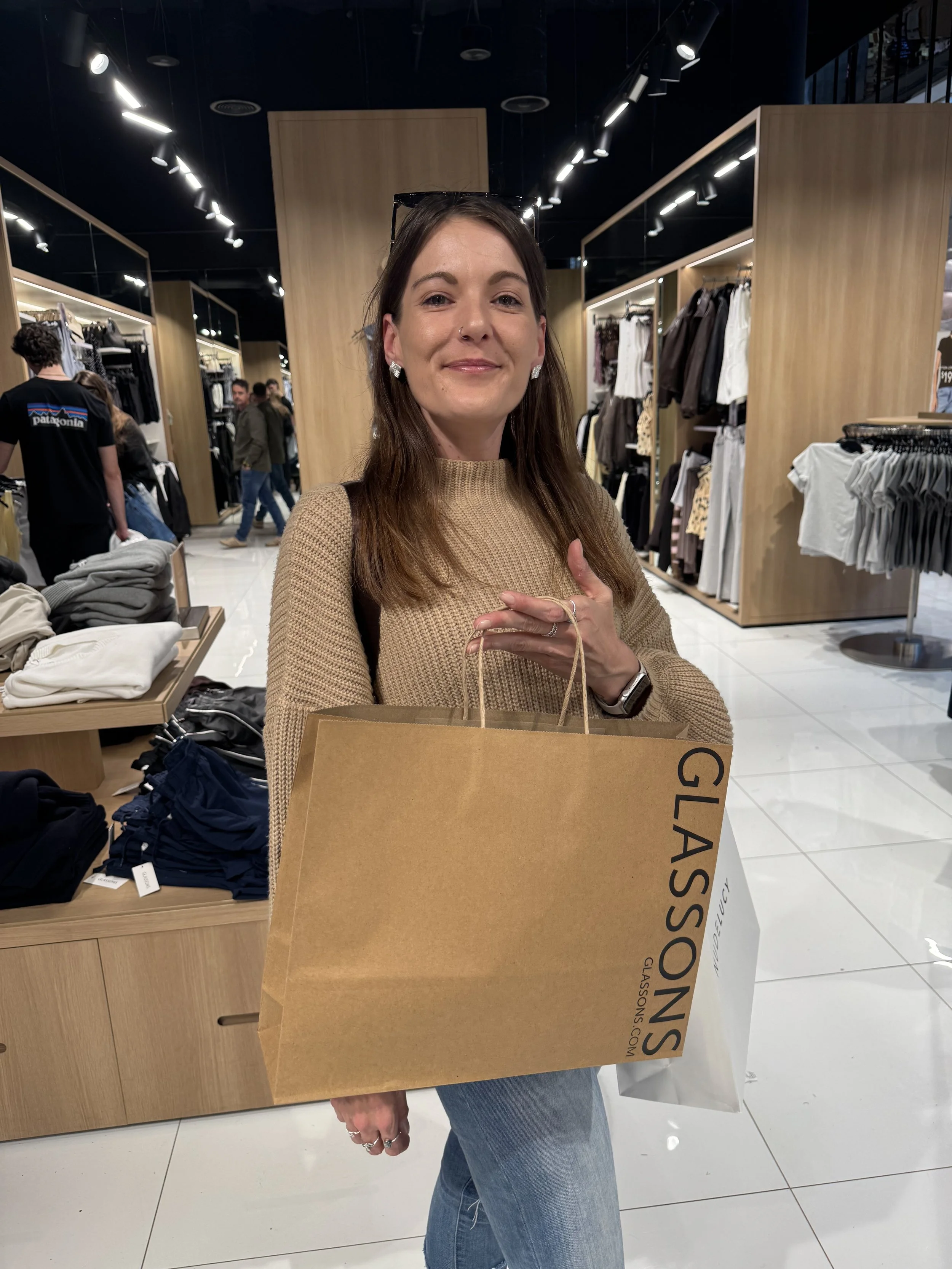 Woman holding shopping bags inside a clothing store.