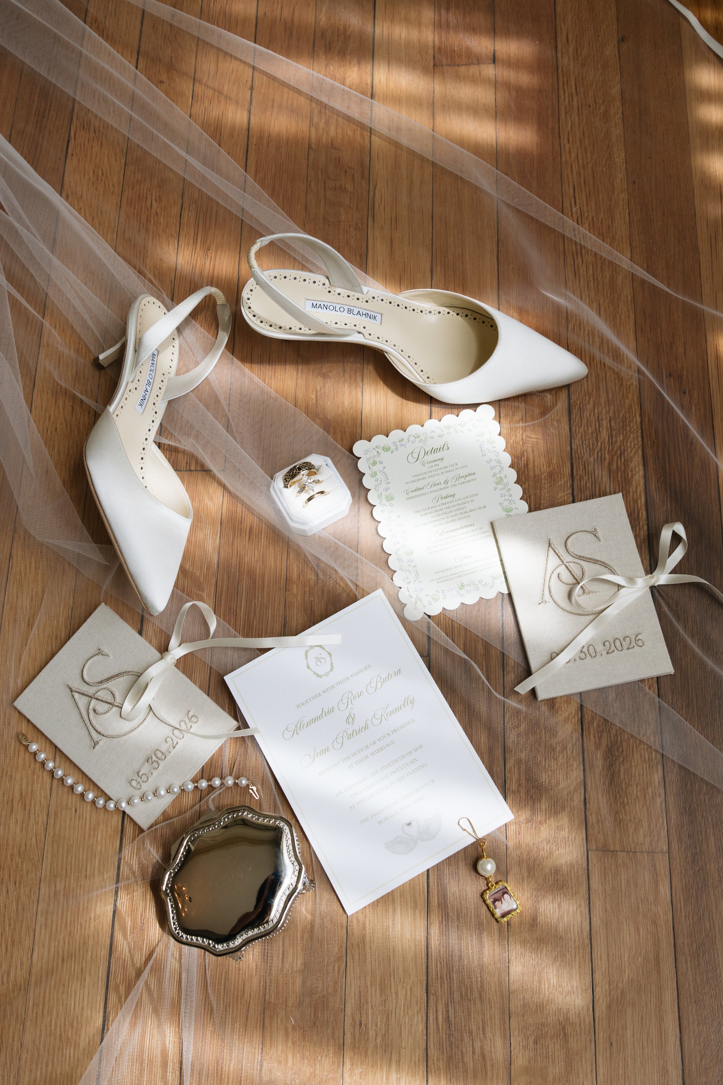 A person wearing a white dress with tulle and pearl embellishments, standing on a wooden floor while wearing pink high-heeled shoes and white socks.