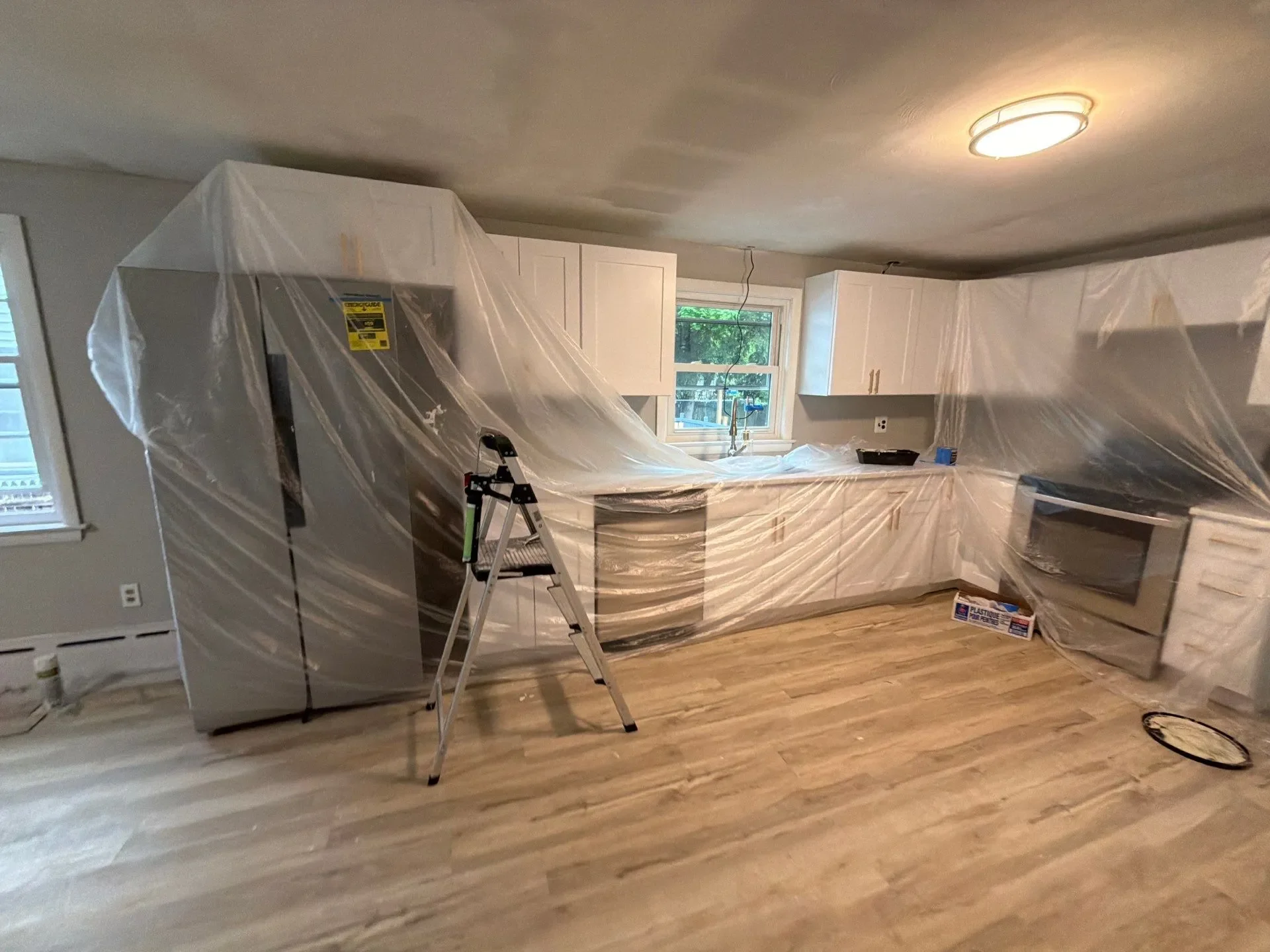 Kitchen cabinets and appliances covered for interior painting in Meriden, CT