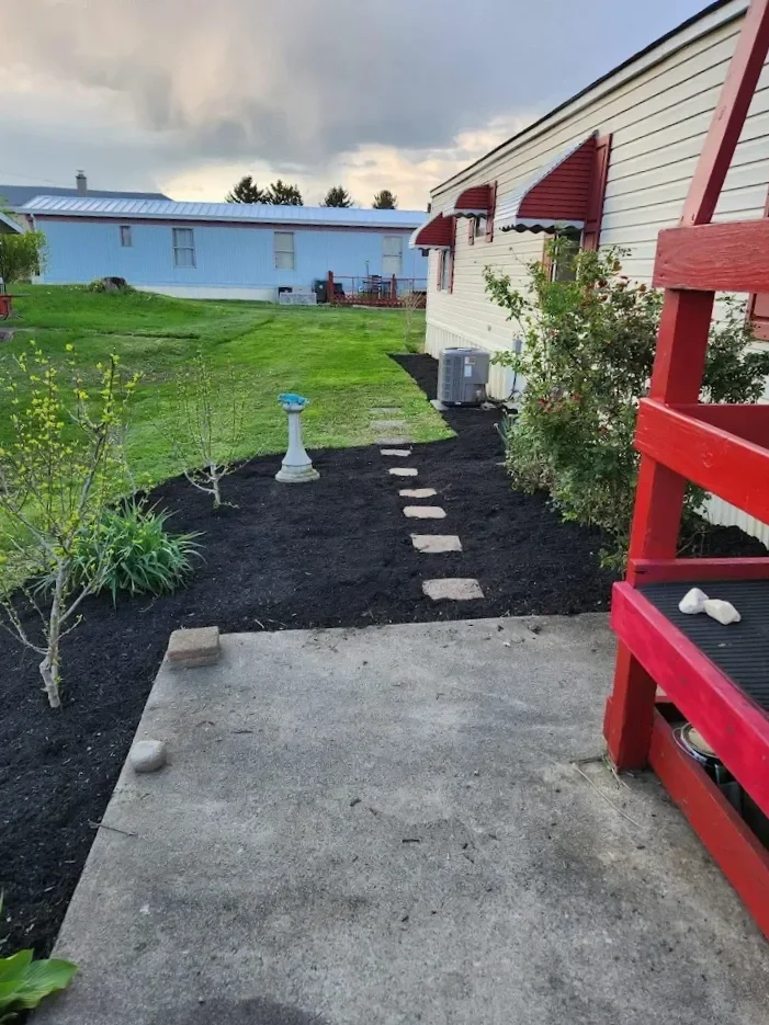Commercial lawn care crew finishing mulch installation along walkway at managed property in New Haven County CT