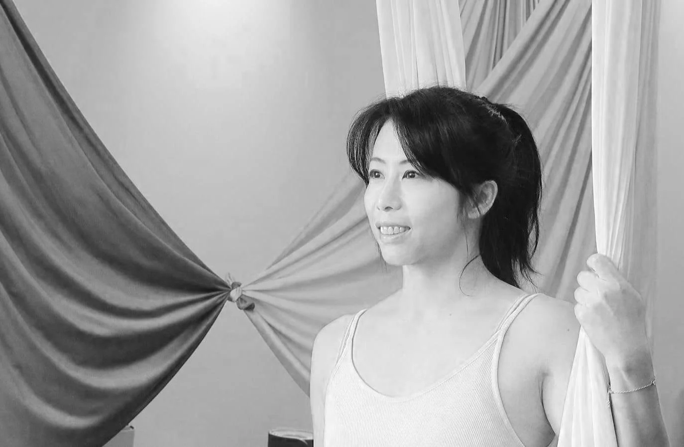 Person holding aerial yoga silks in a studio.