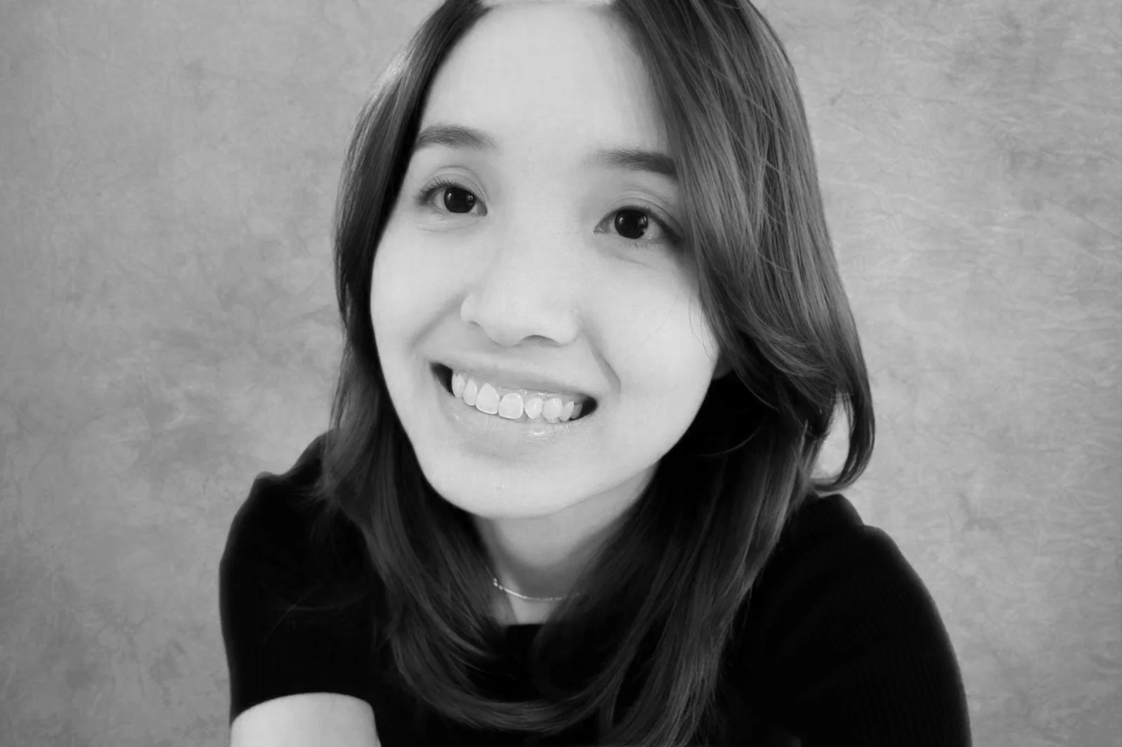 Black and white portrait of a woman with shoulder-length hair smiling.