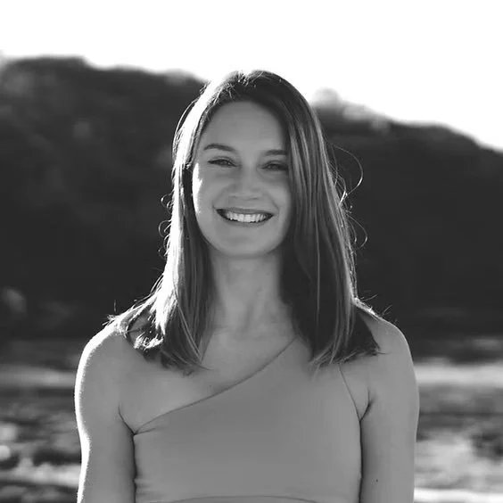 Smiling woman in a one-shoulder top; black and white photo.