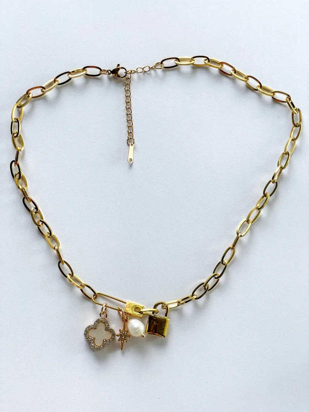 Gold paperclip chain charm necklace with opal clover and love locket charm on white background