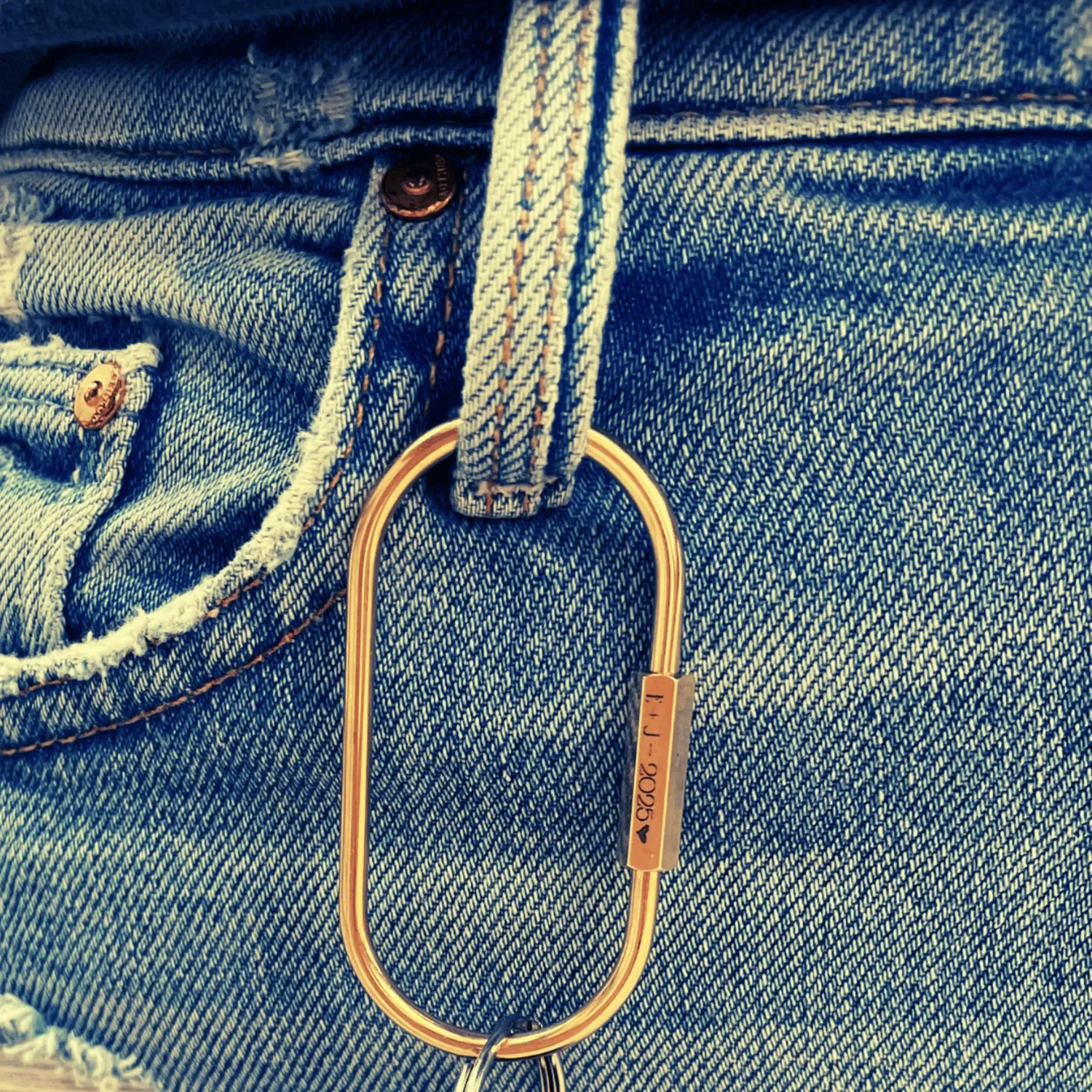 Engraved small brass keyring secured on models jeans