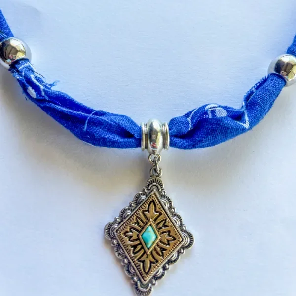 Close-up of antique silver Native American charm on blue bandana necklace