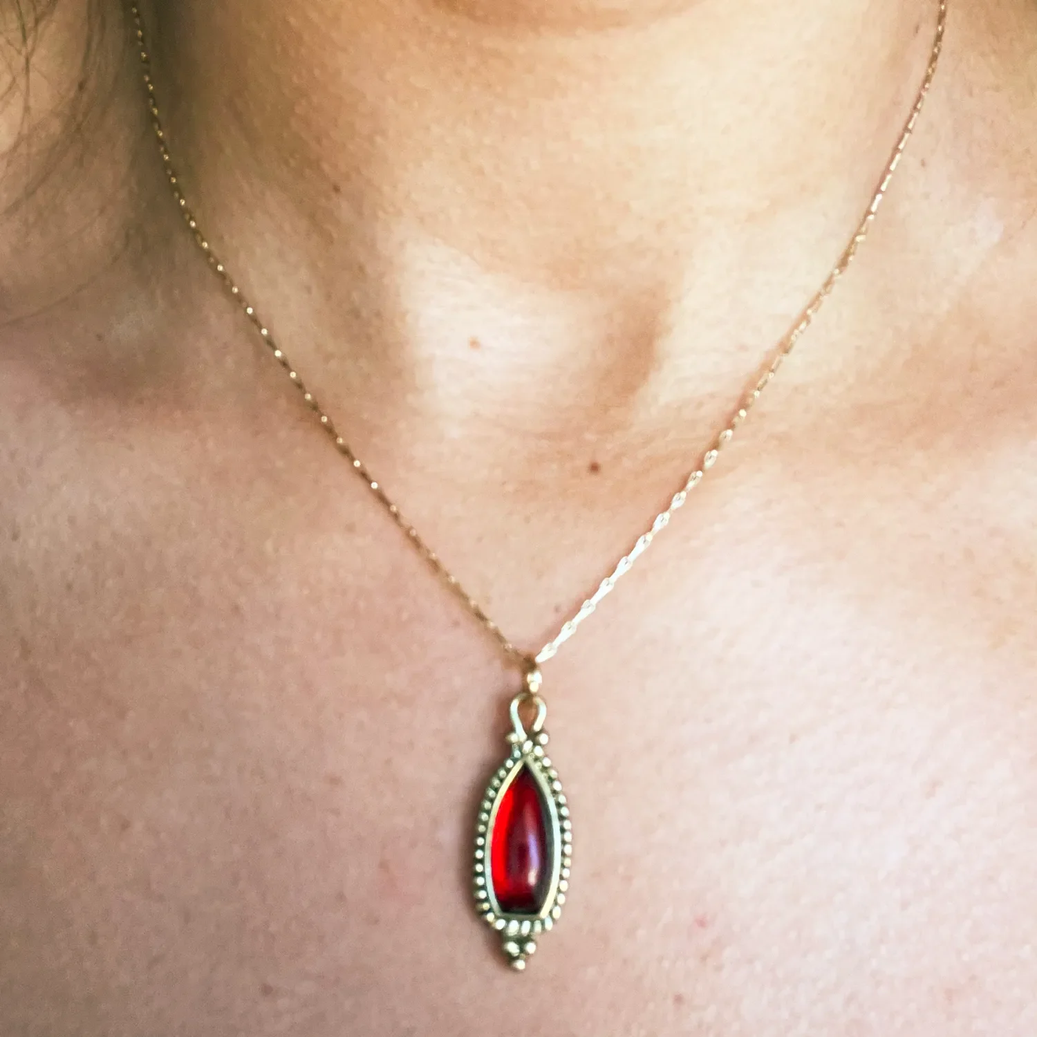 A delicate balance of vintage charm and understated elegance — featuring a deep red garnet drop pendant suspended from a fine gold-plated dog-bone chain.