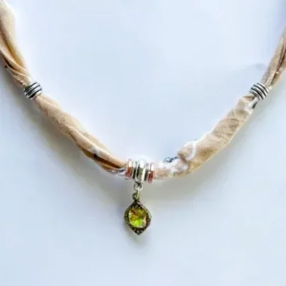 Close-up of Blush Bandana Charm Necklace center pendant — petite antique bronze geode-style charm with iridescent green and amber aurora stone
