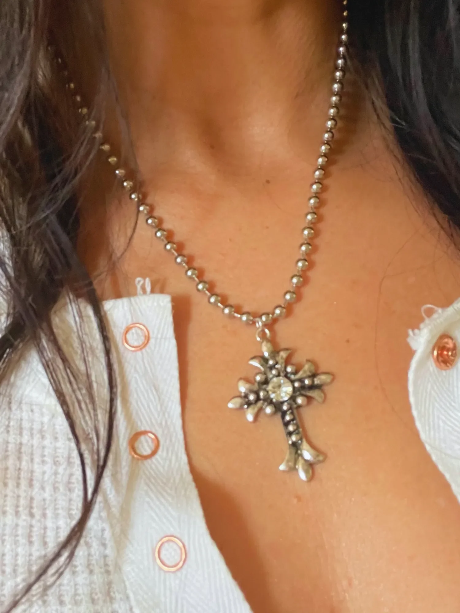 Close-up on model wearing Gothic Cross Necklace Woman wearing antique silver Gothic Cross Necklace on a 16-inch stainless steel ball chain with Swarovski crystal pendant.