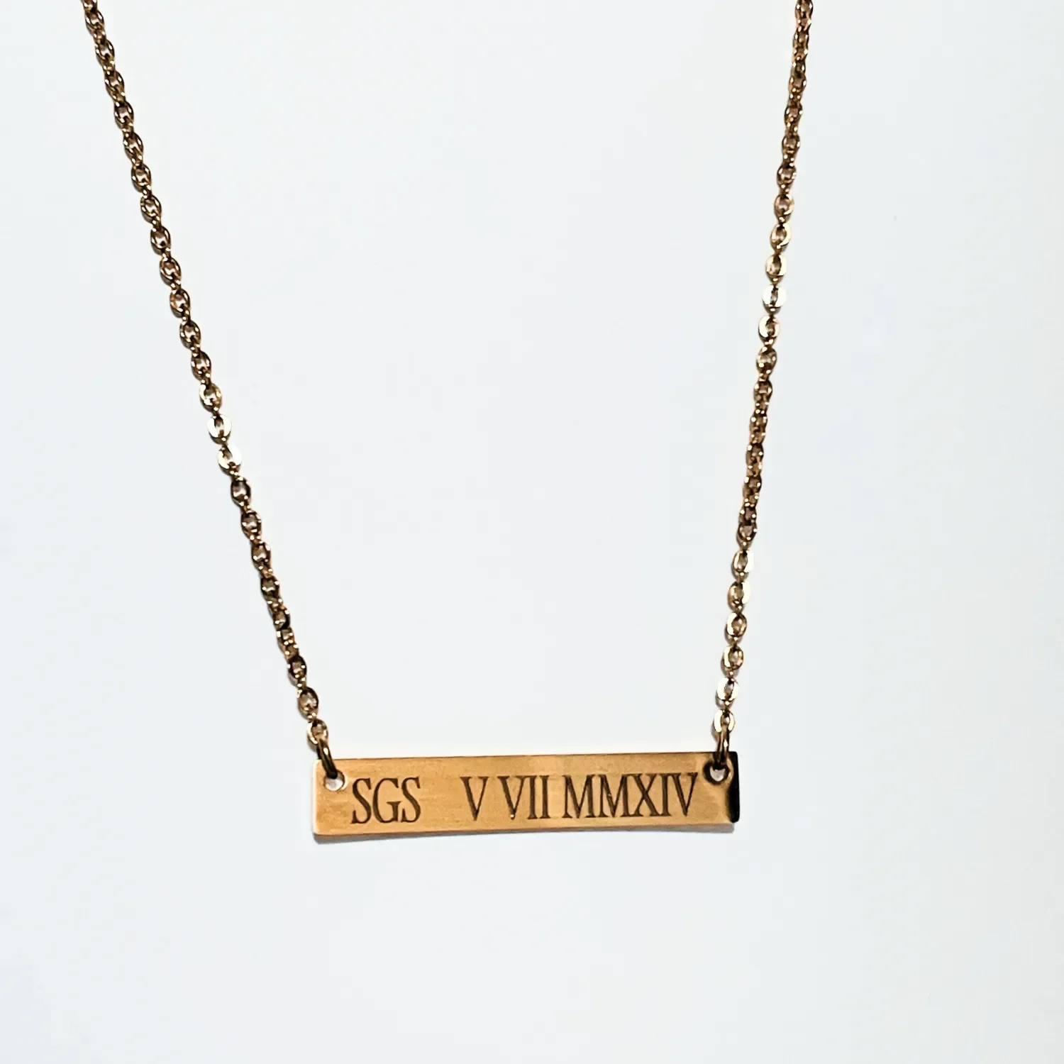 Engraved gold bar necklace featuring 14k gold plated rectangular nameplate with custom Roman numeral engraving on minimalist chain.