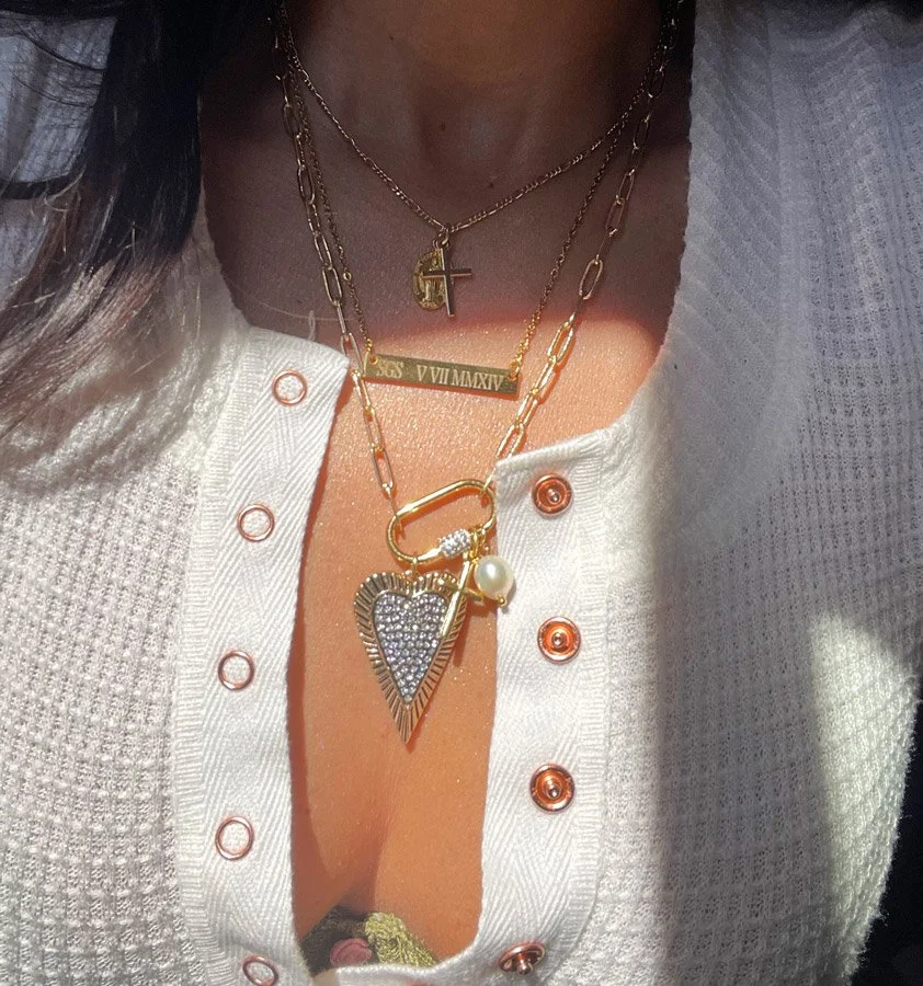Pavé Heart Carabiner Charm Necklace displayed on white background showing gold paperclip chain, cubic zirconia heart pendant, pearl, rose, and cross charms.