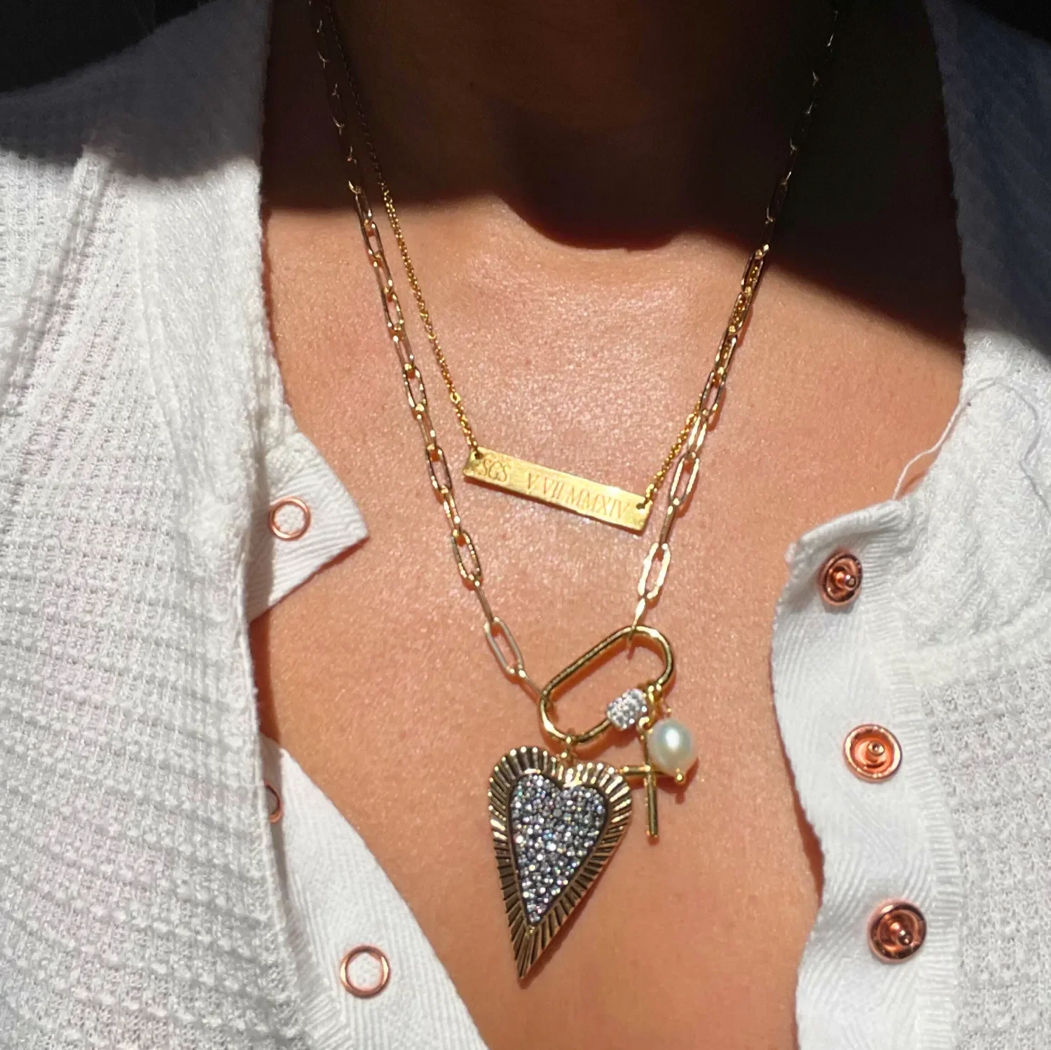 Woman wearing Babe’s Hardware Pavé Heart Carabiner Necklace layered with engraved gold bar necklace, showing gold paperclip chain and pavé heart pendant.