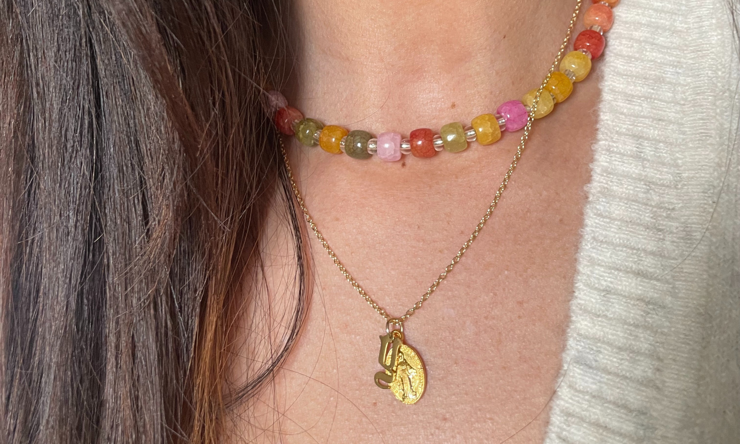 Female model wearing a gold Miraculous Medal Virgin Mary and gothic initial pendant necklace