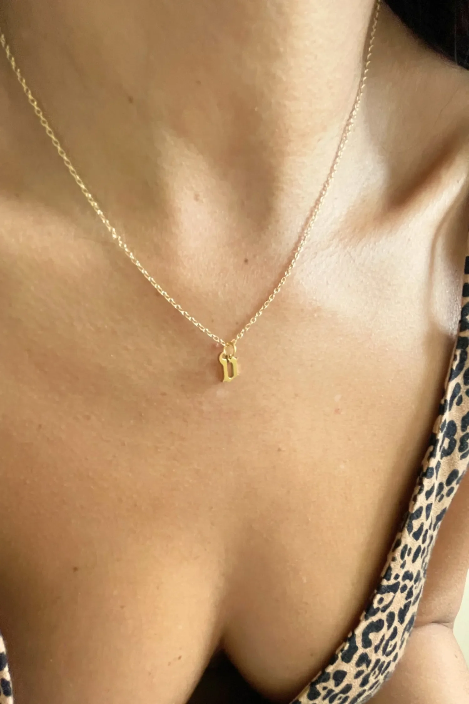 Woman wearing gold gothic letter "v" necklace