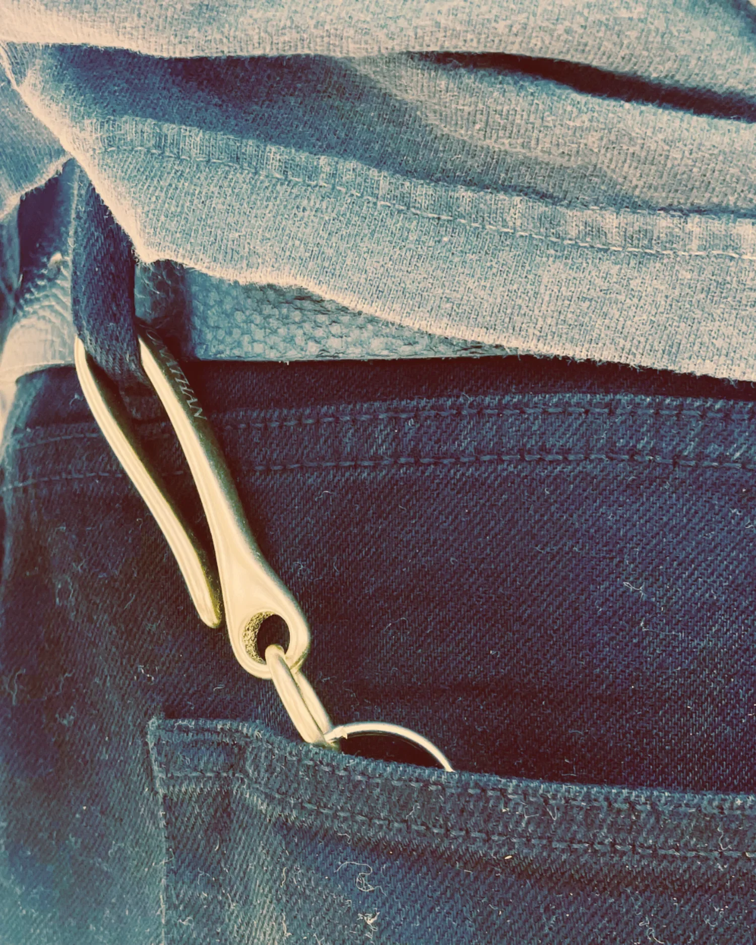 Male model wearing Engraved brass fish hook keychain with Old English name engraving, hooked onto his belt loop pocket