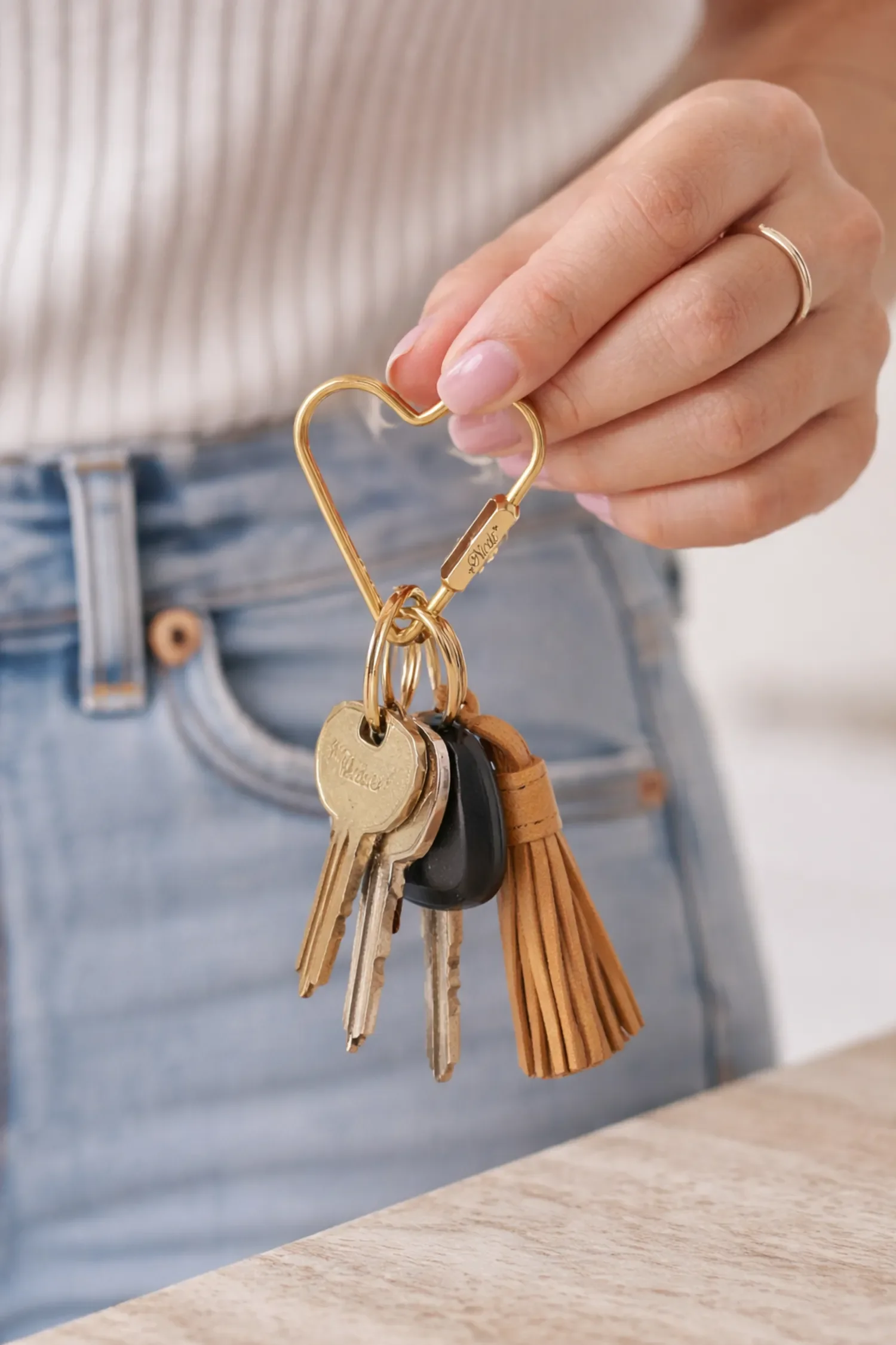 Women holding brass heart carabiner keychain engraved with name "Nicole" on locking screw by Babe's Hardware