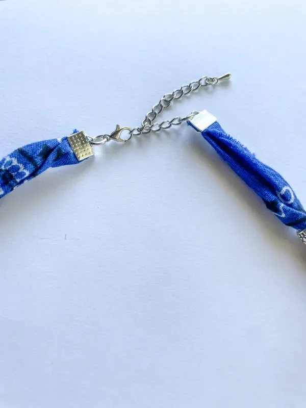 Close-up of Southwestern Bandana Charm Necklace silver lobster clasp and adjustable extension chain — silver crimp end caps securing twisted navy blue bandana cord ends.