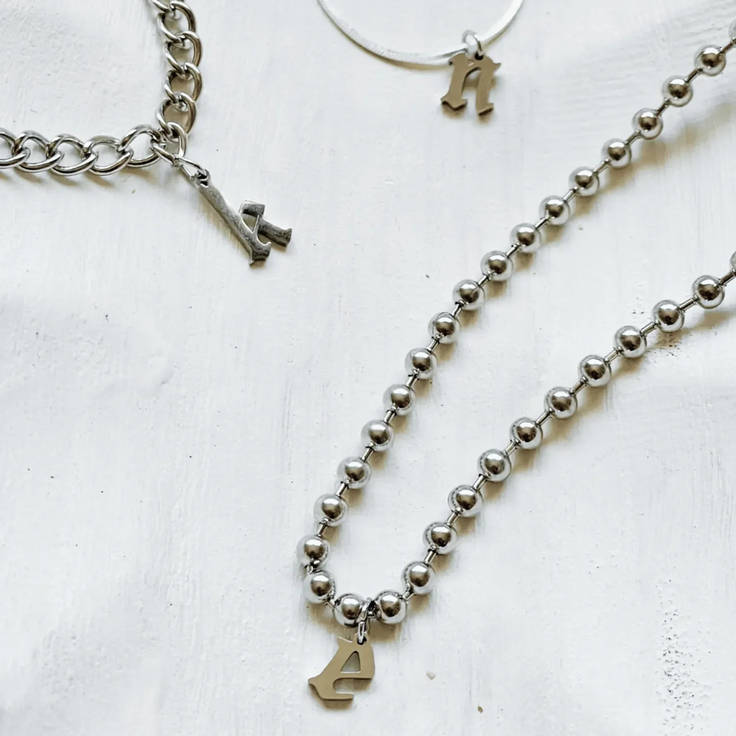 Sterling silver gothic initial necklace styled with layered chains