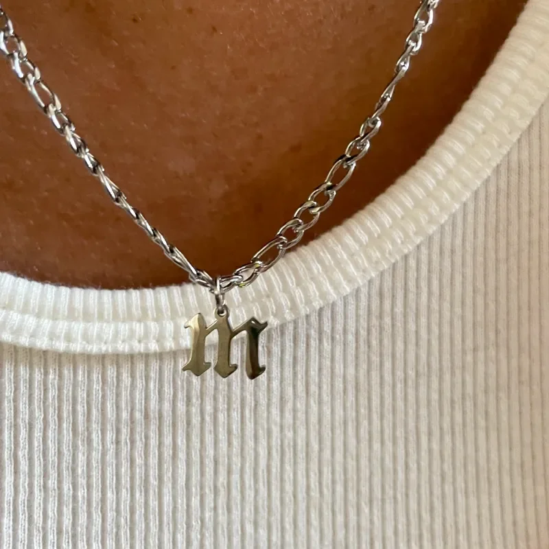 woman wearing silver necklace with gothic initial "m" pendant