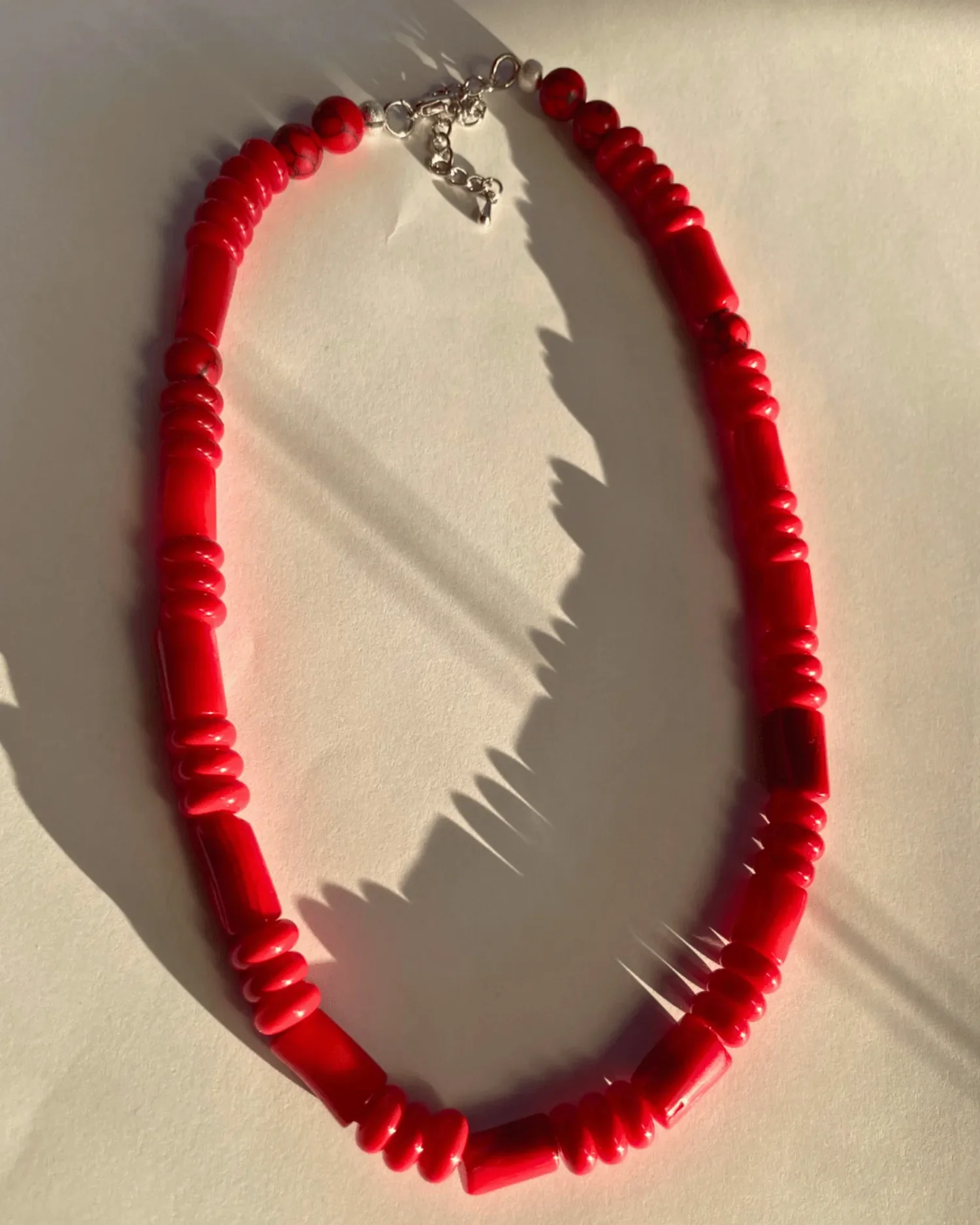 Close-up of The Scarlett Necklace, a handcrafted red beaded necklace with sterling silver hardware and lobster clasp.