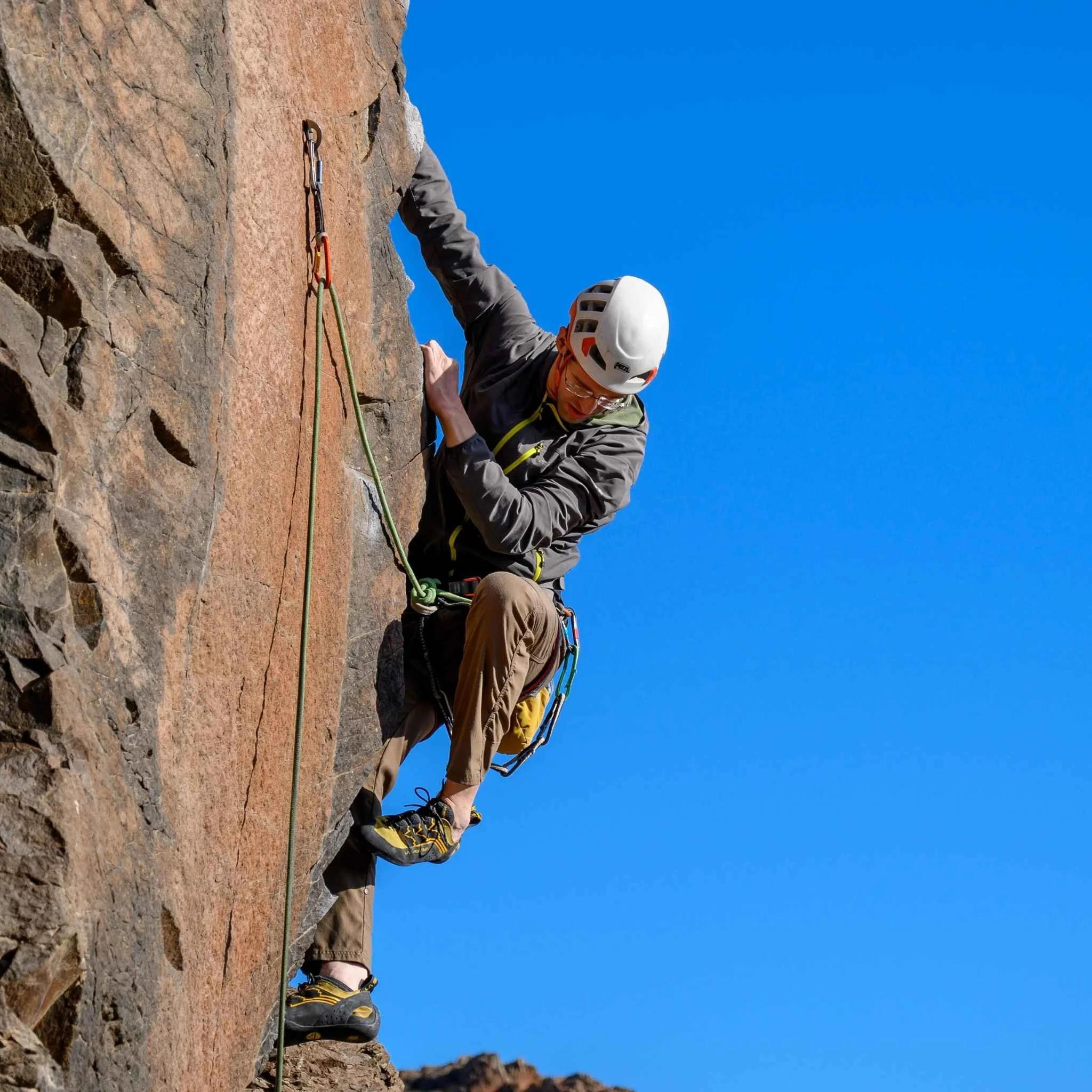 A rock climber ascending a sport climbing route outside