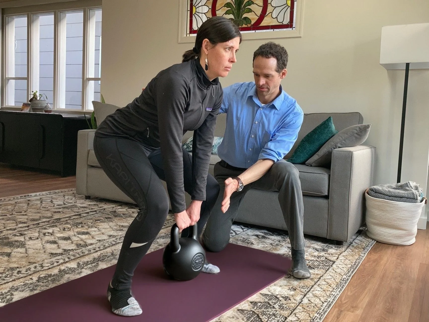 Physical therapist providing in-home physical therapy in Everett, WA, coaching proper squat form during a one-on-one session