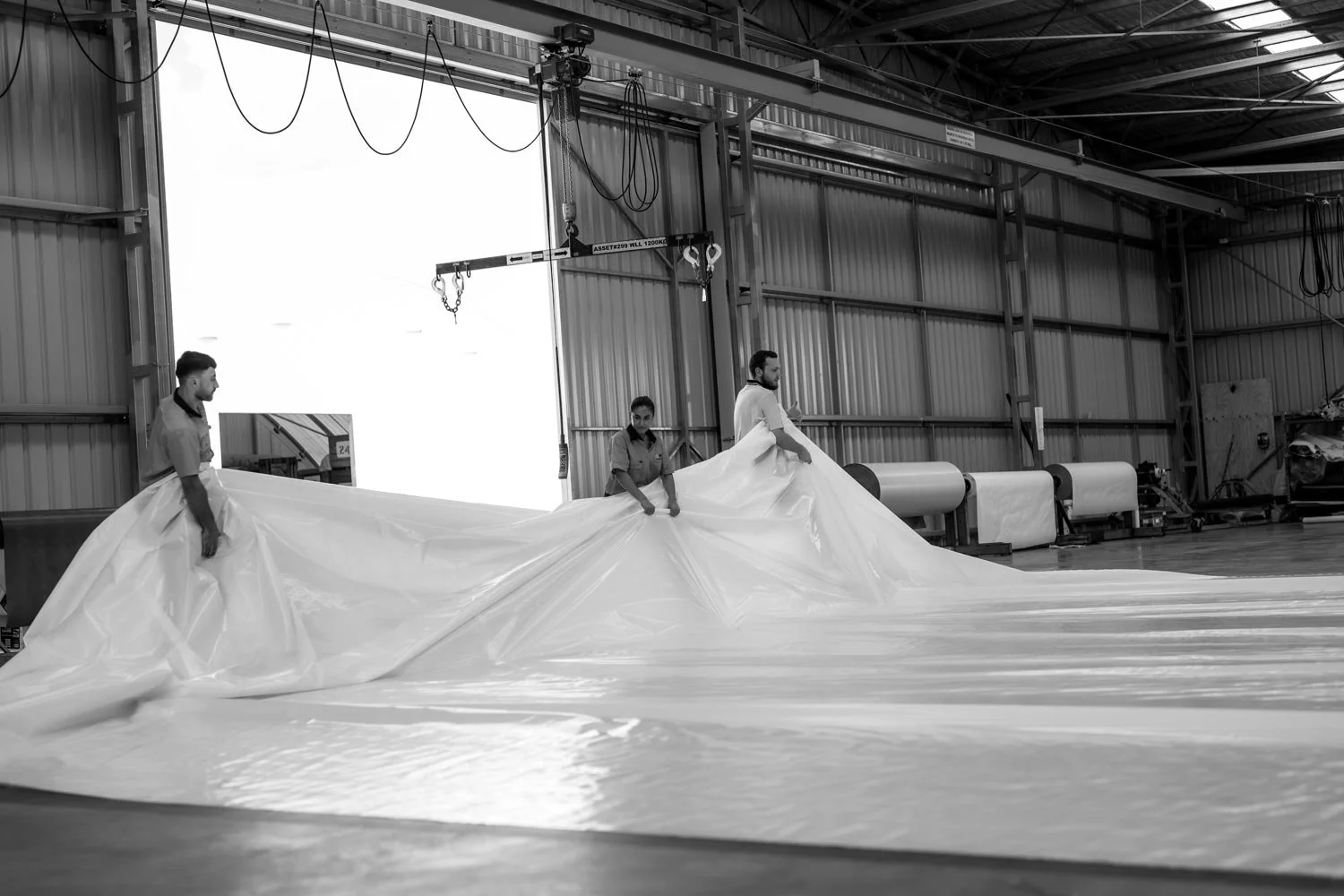 three-people-rolling-a-huge-tarpaulin.jpg
