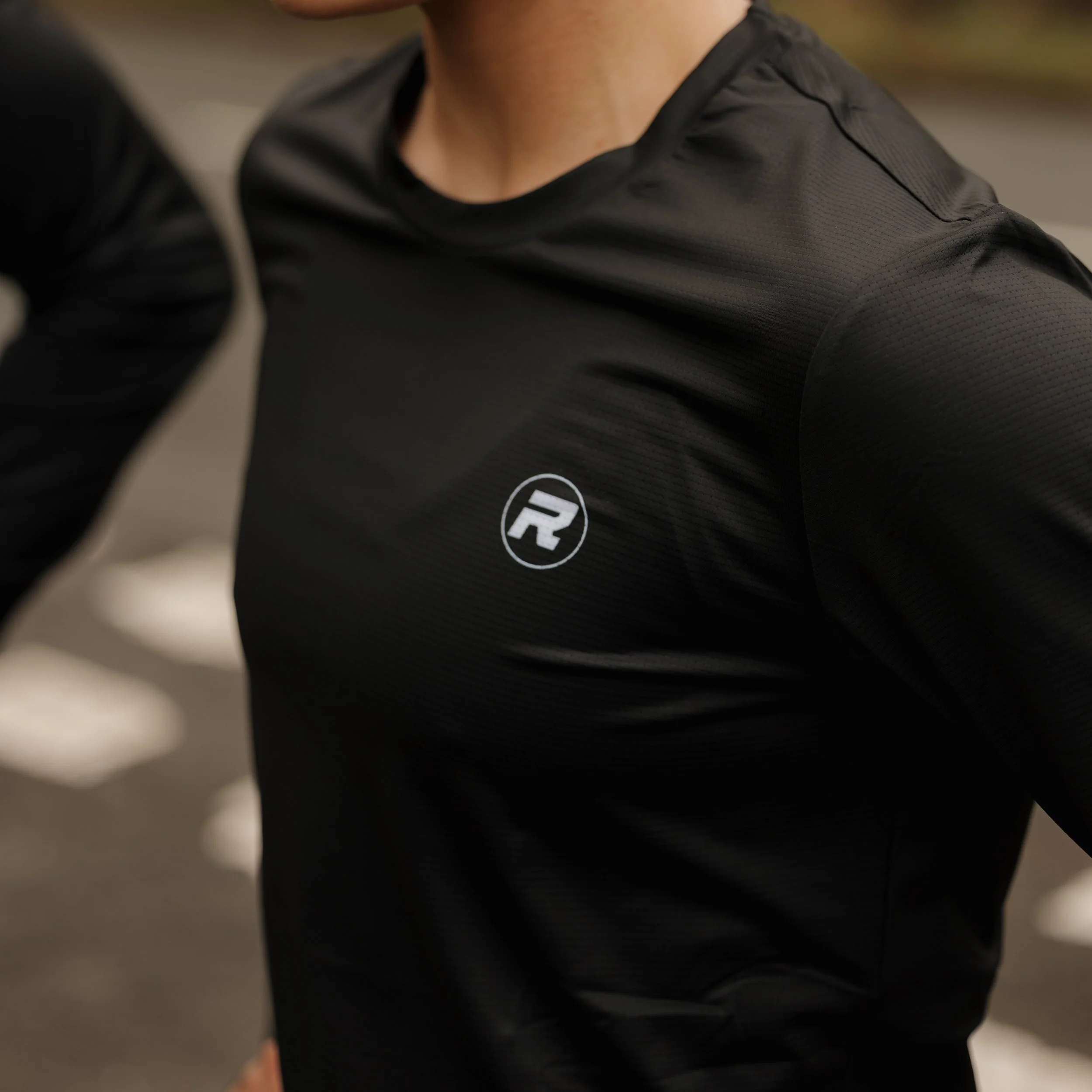 Close-up of a person wearing a black athletic shirt with a small logo on the chest.