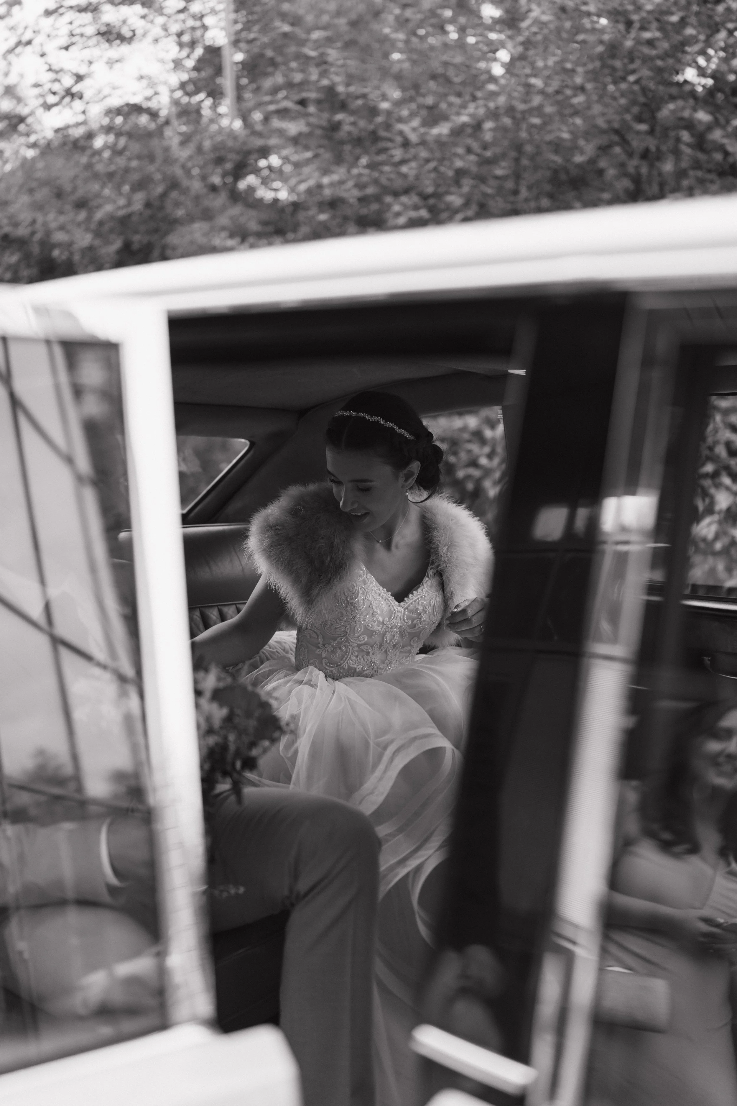 Bride in white lace dress holding a bouquet of white roses and greenery.