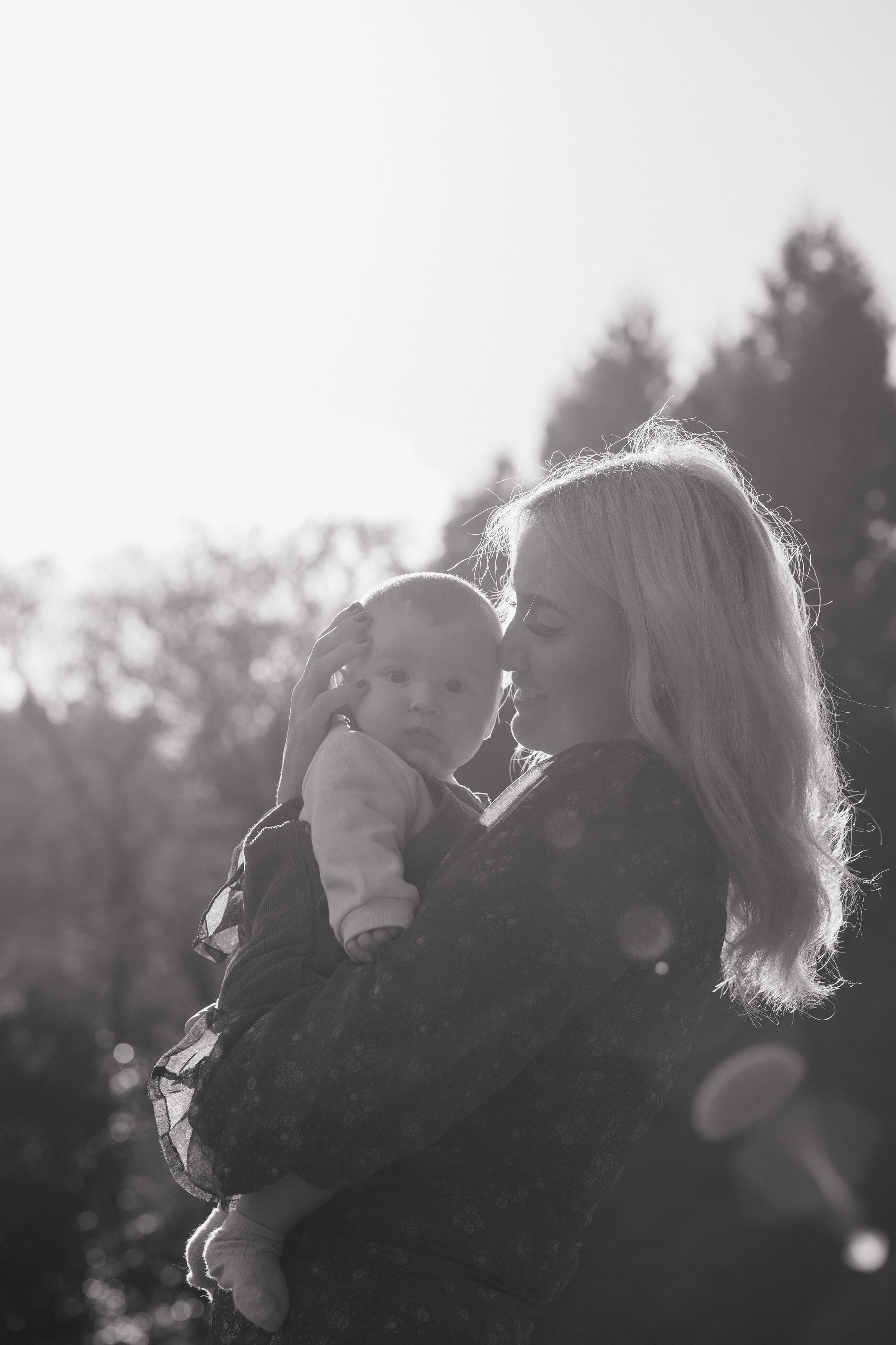 A woman holding a baby outdoors in black and white.