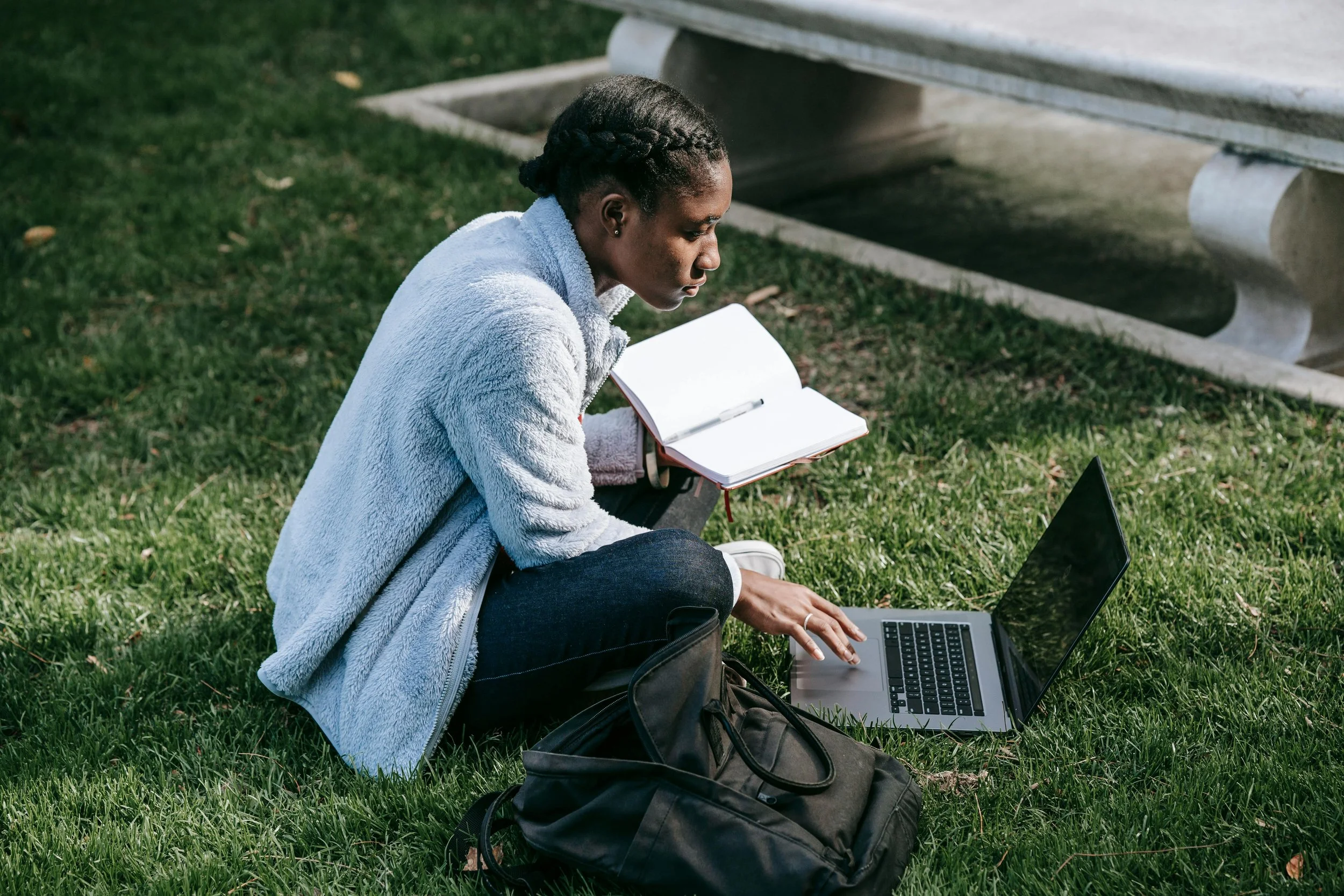 College student sitting on the grass doing work