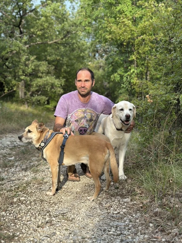Handsome man with two dogs smiling with the sunset light shining on them.