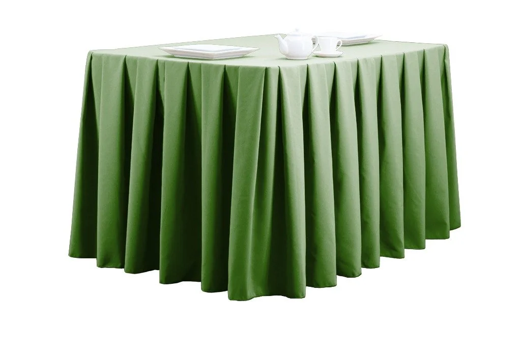 Round table with a green tablecloth, set with white teapot, cups, saucers, and plates