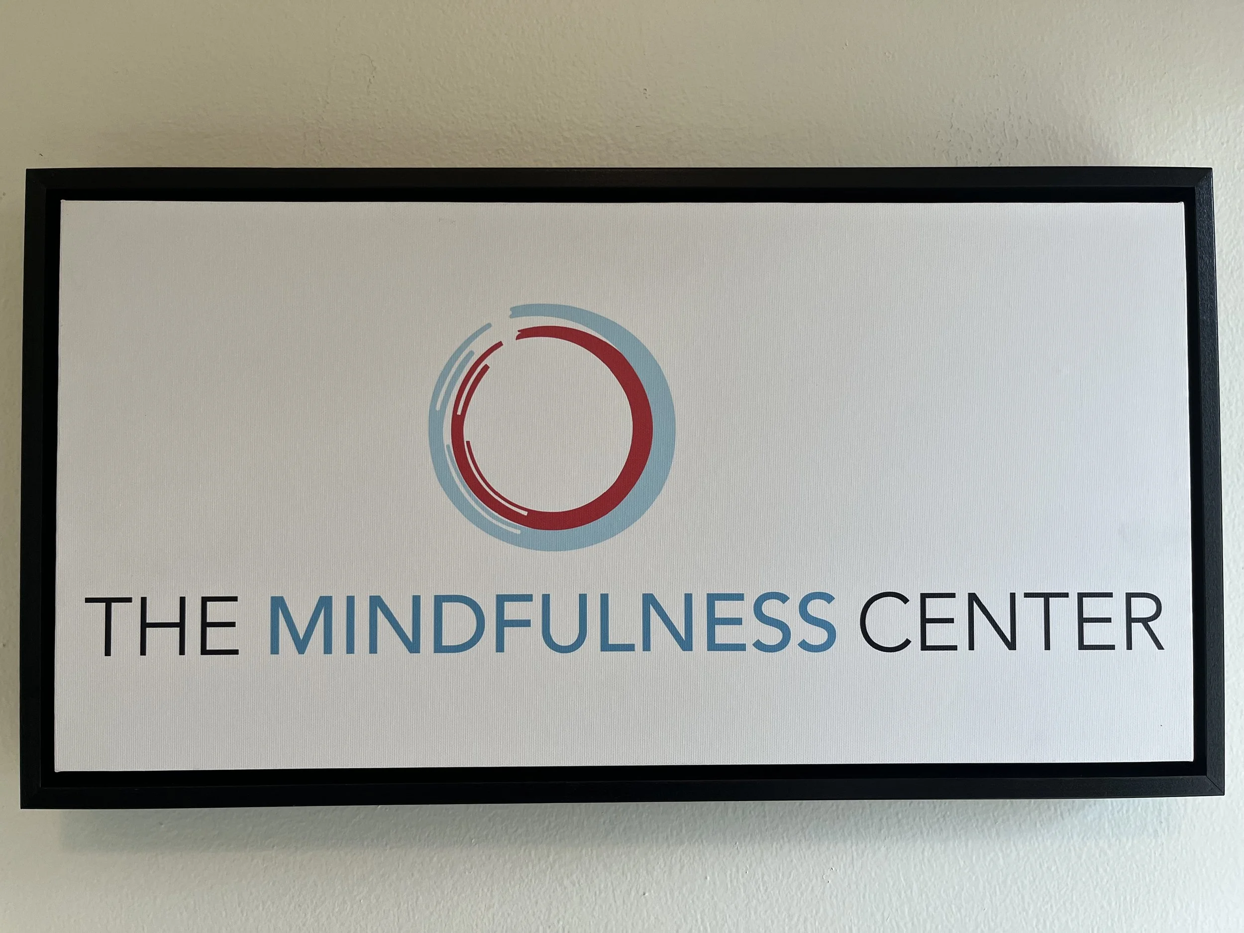 The Mindfulness Center sign + logo; two circles — out circle is light blue and inner circle is red; the words "The Mindfulness Center" are underneath the logo