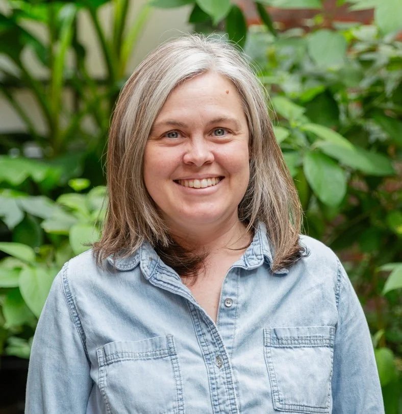 Portrait of a woman with shoulder length hair, wearing a blue button down shirt.