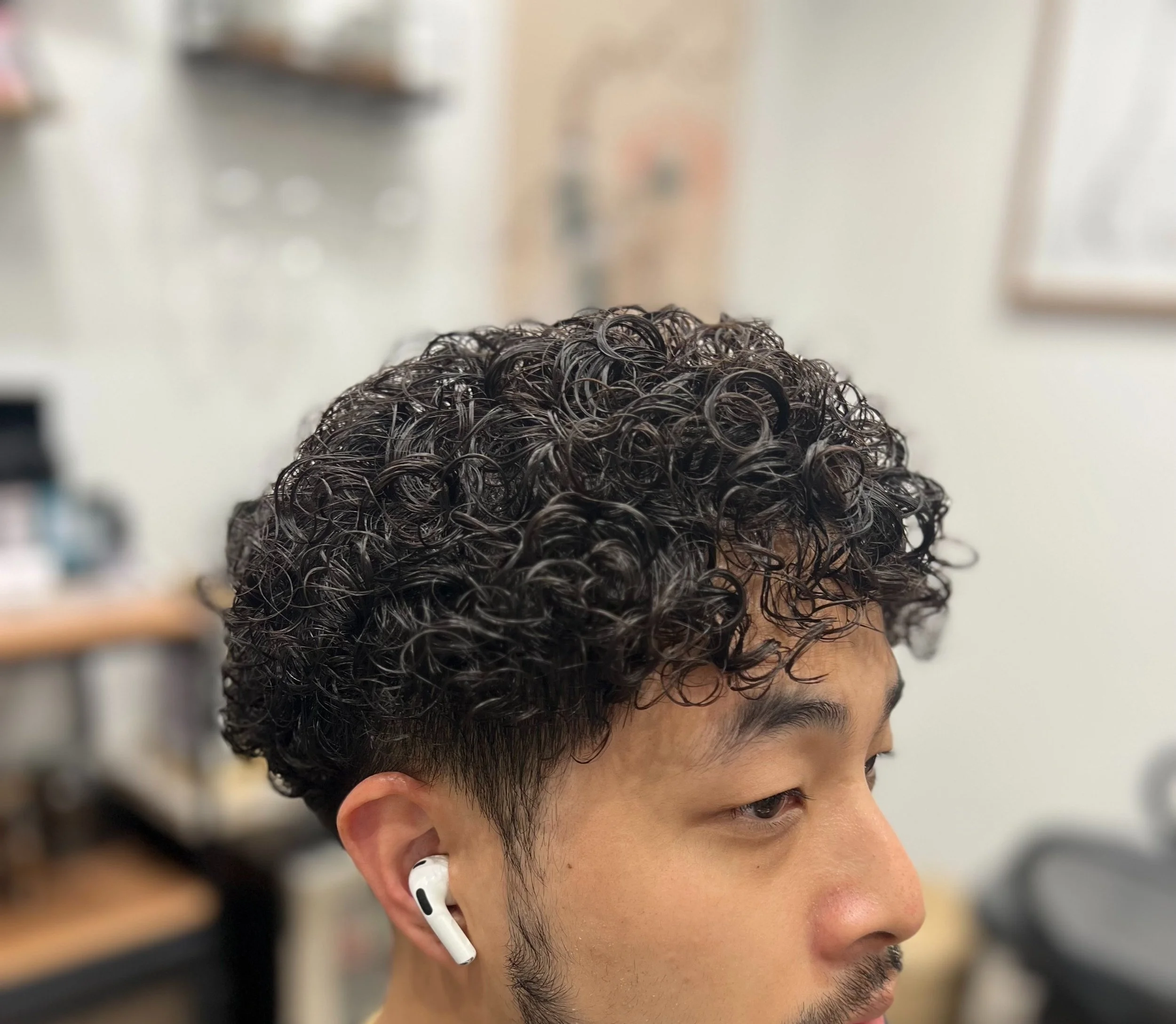 Man with curly hair wearing white earbuds