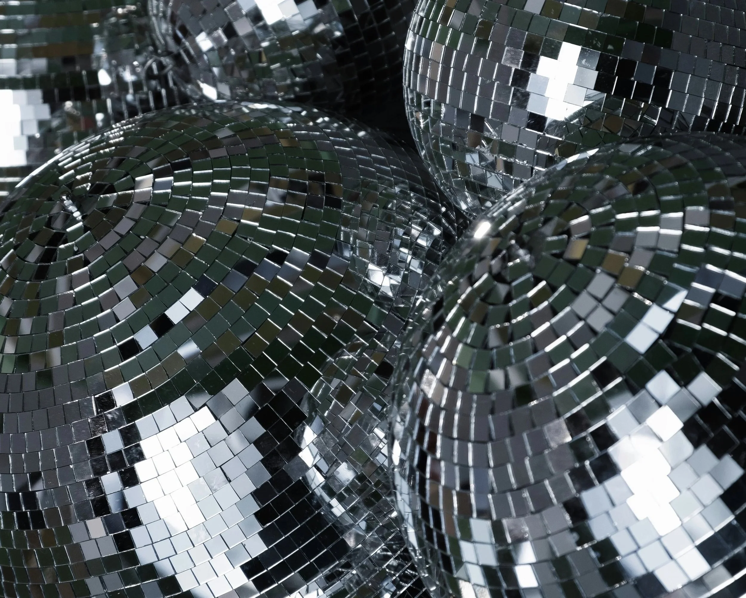 Close-up of rolled-up metallic disco mirror balls with reflective square tiles.